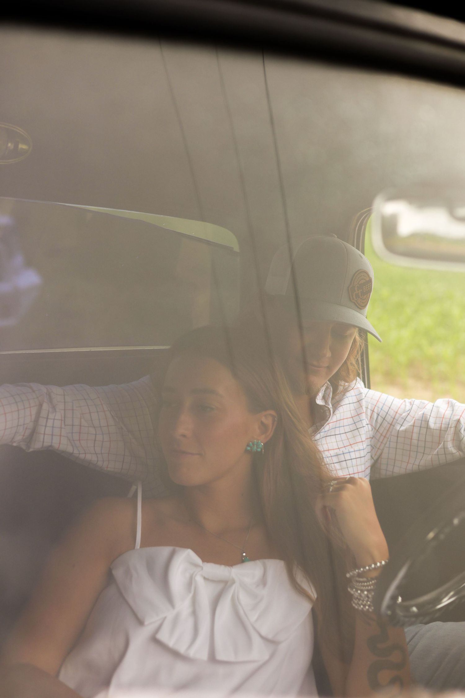 A tender moment unfolds inside a car as sunlight filters through the windows.