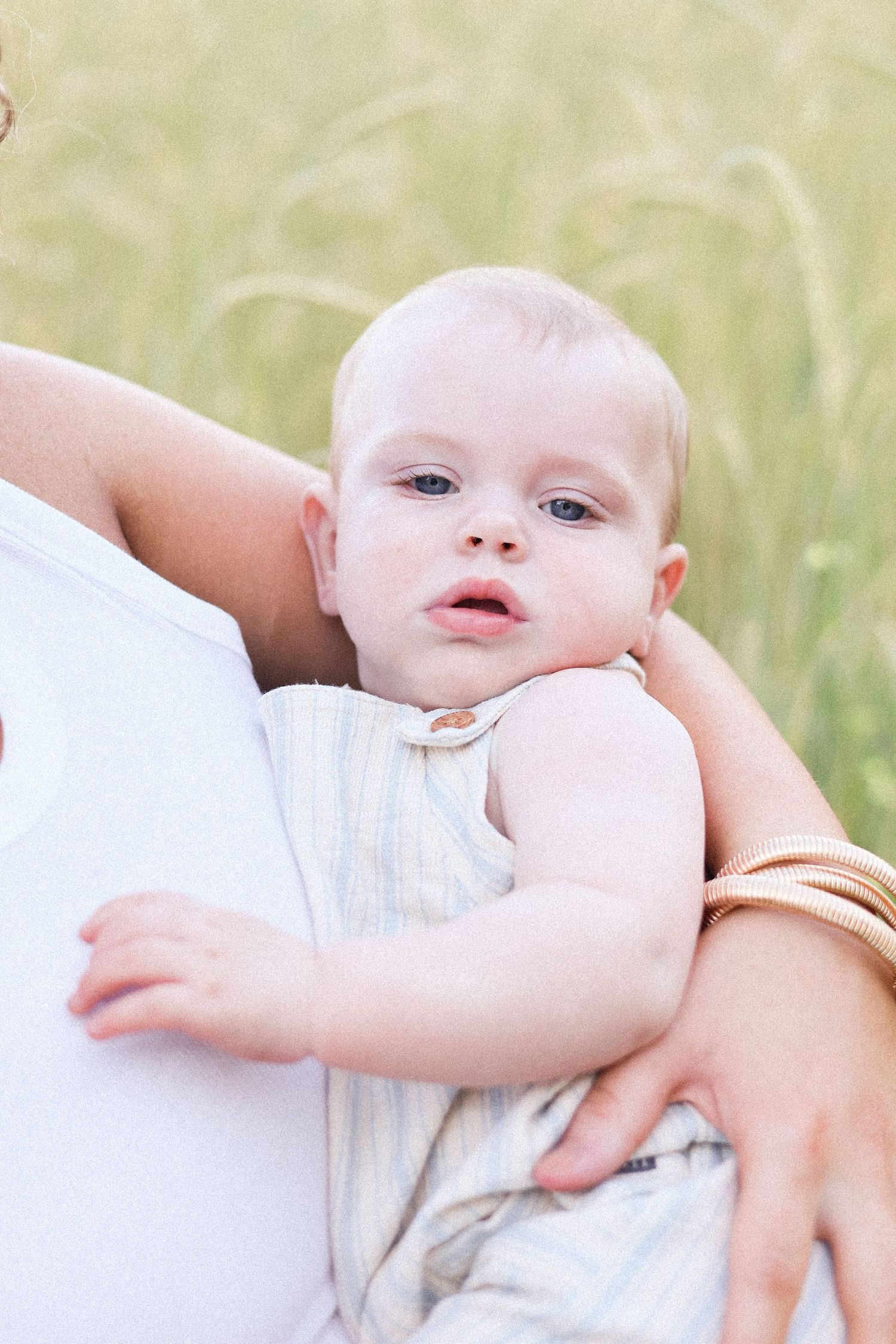 Baby in white clothing resting peacefully against soft neutral background.