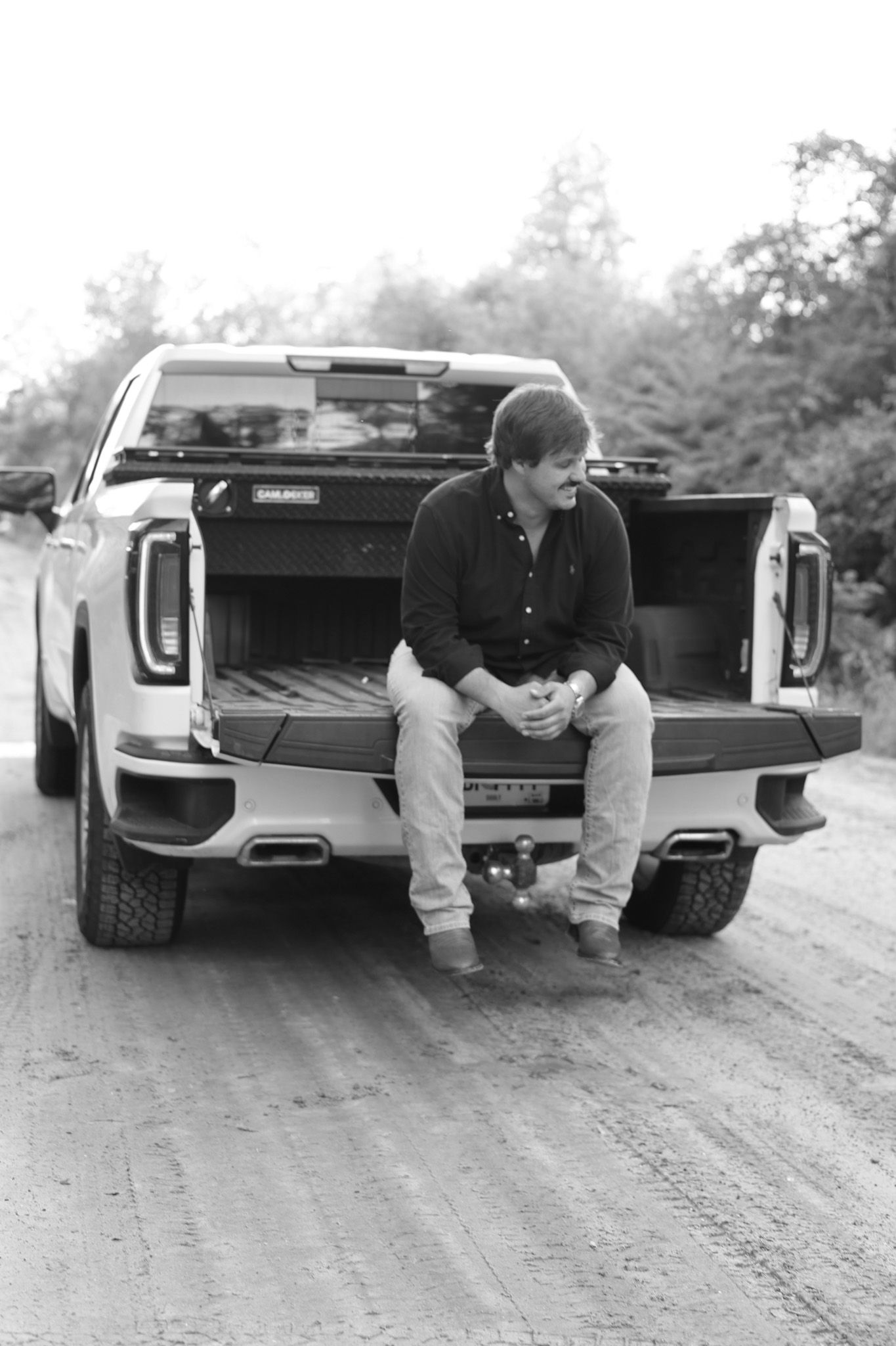 Black and white photos of person sitting in pickup truck bed.