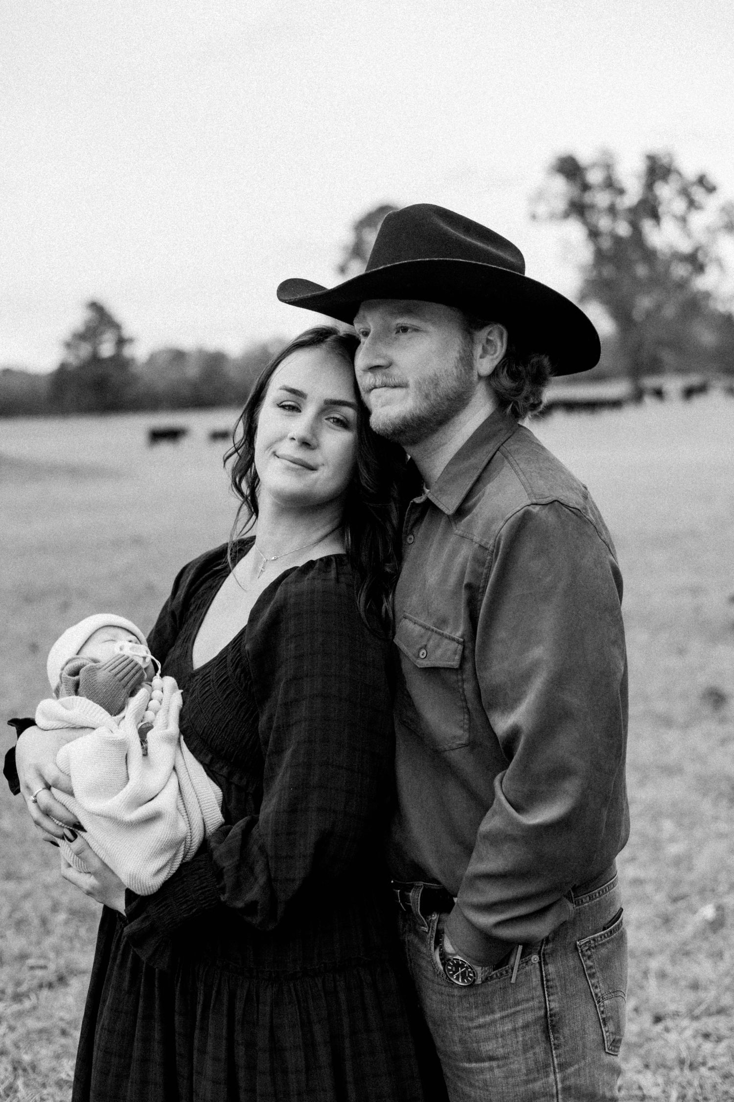 Family portrait series showing tender moments with a newborn baby in a country field.