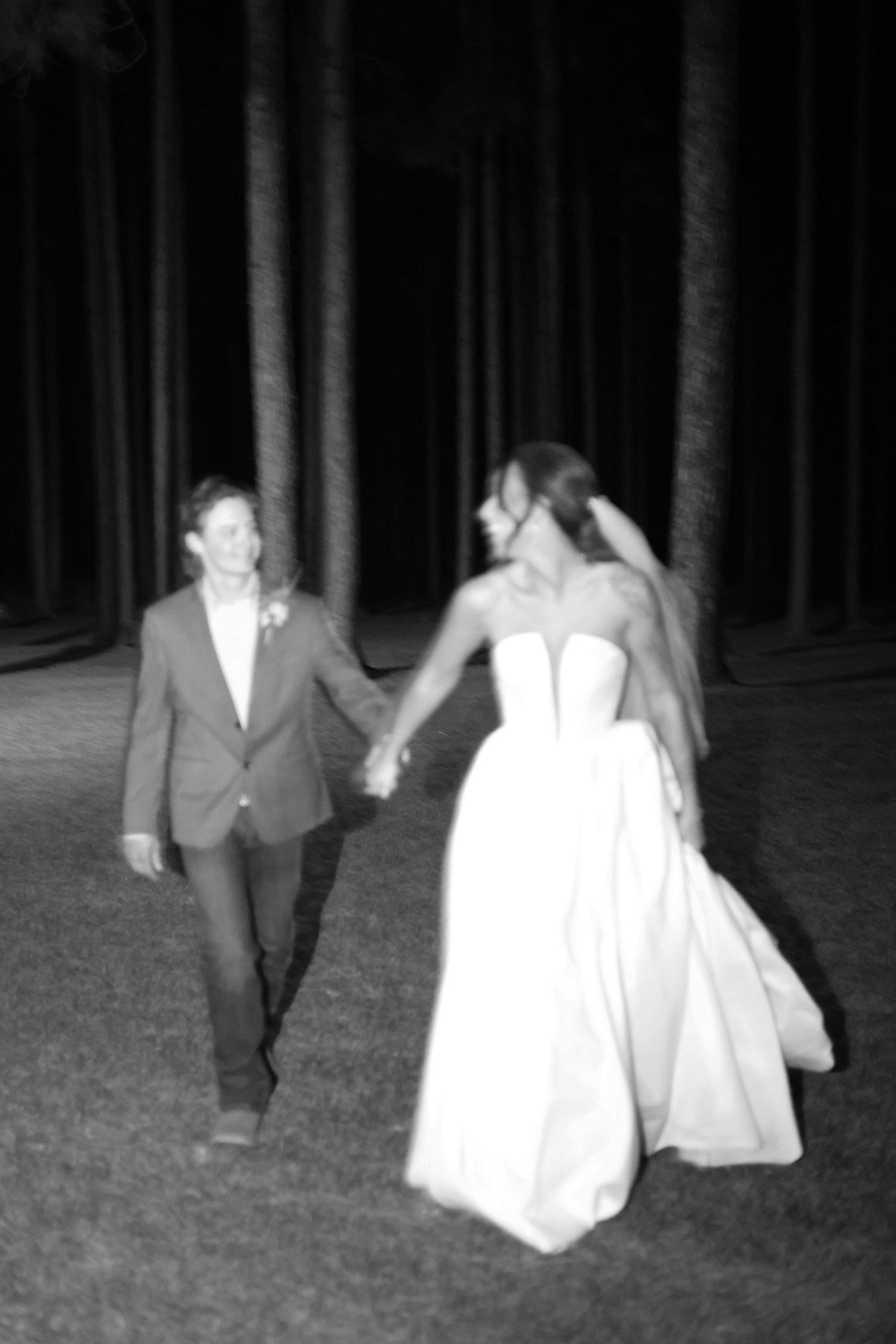 Black and white photos of a couple walking through a dark wooded area at night.