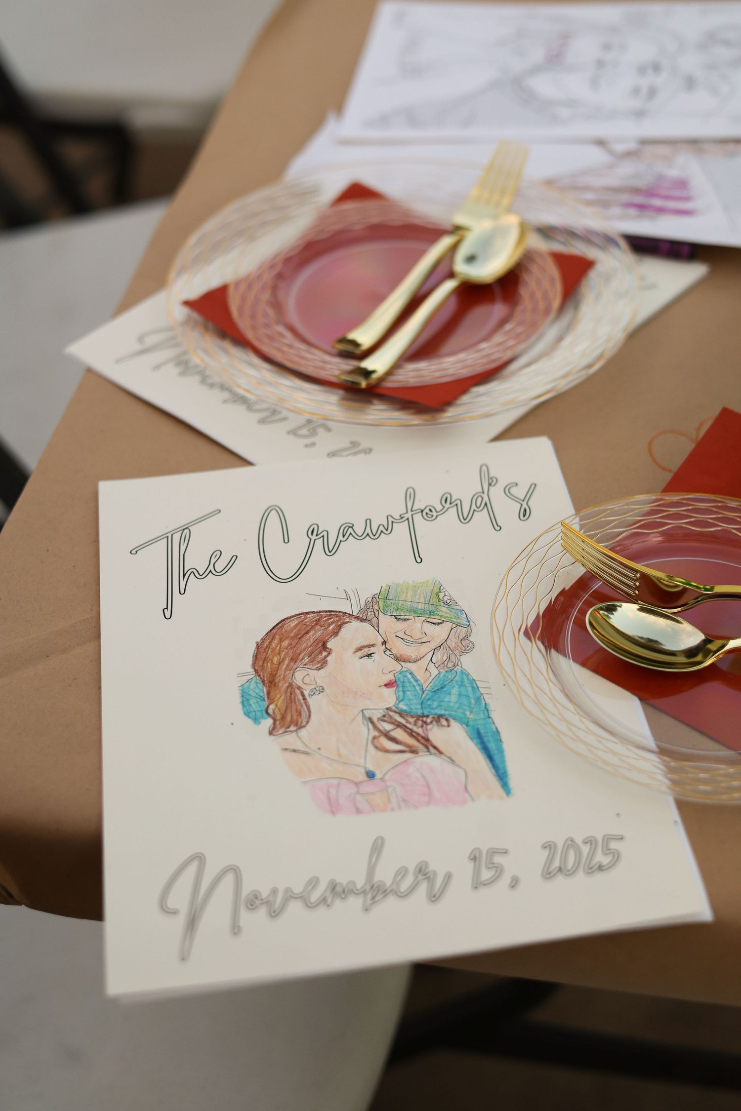 Wedding place cards with delicate watercolor illustrations and gold utensils on a brown surface.