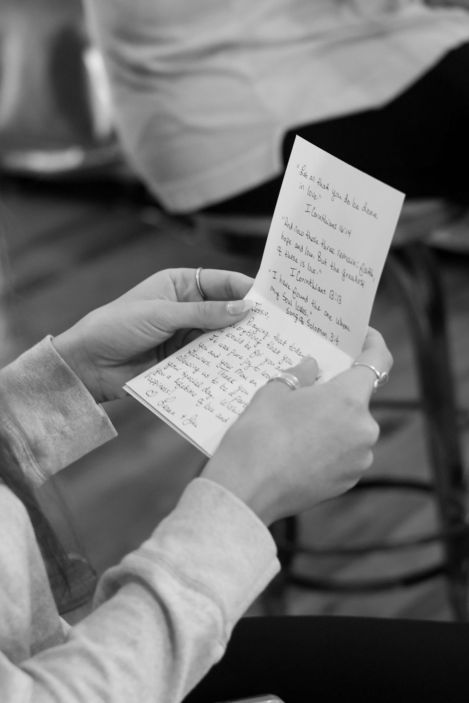 Hands holding and reading a handwritten love letter or note in black and white.
