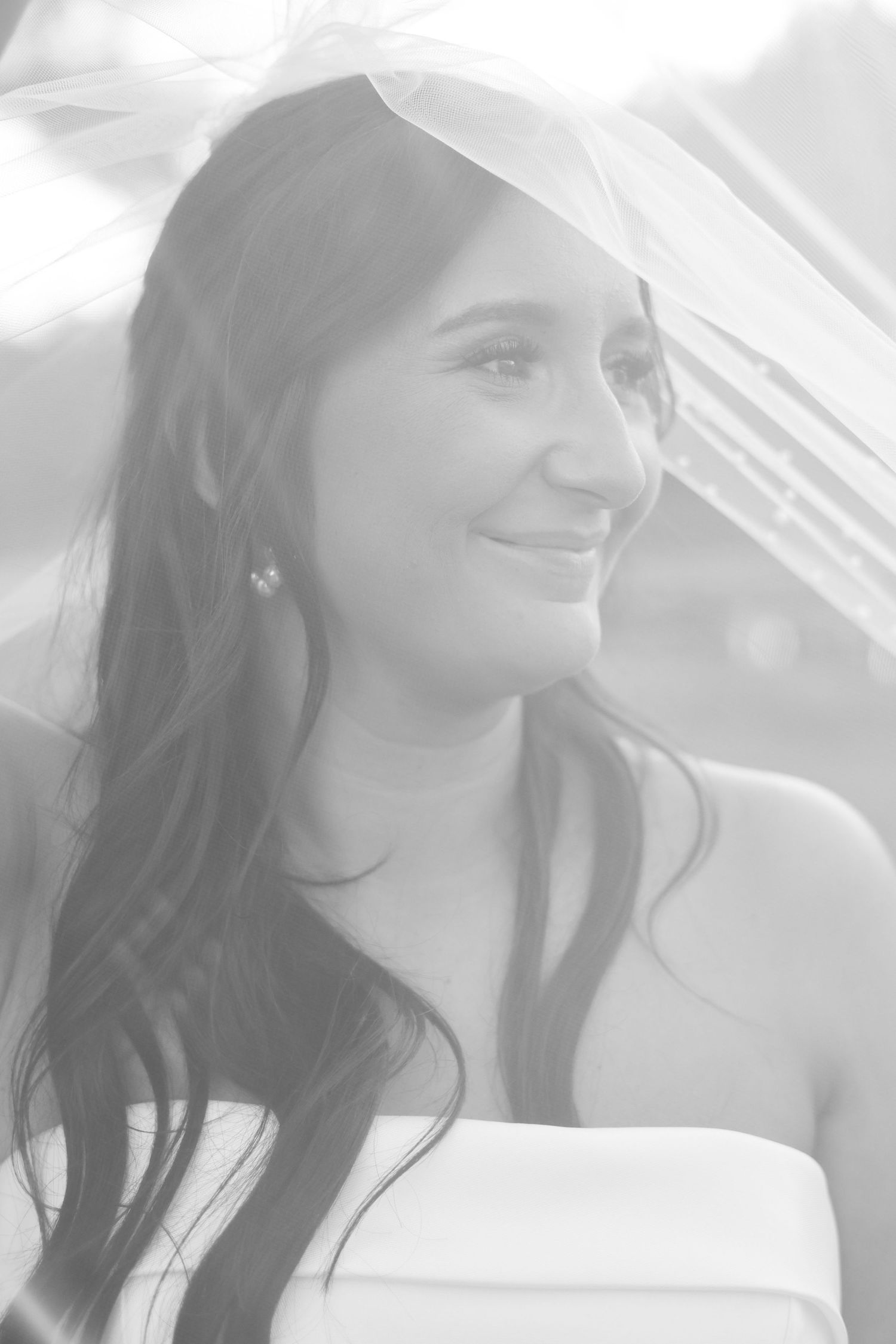 Soft ethereal bridal portraits show joyful expressions through delicate veil in natural light.