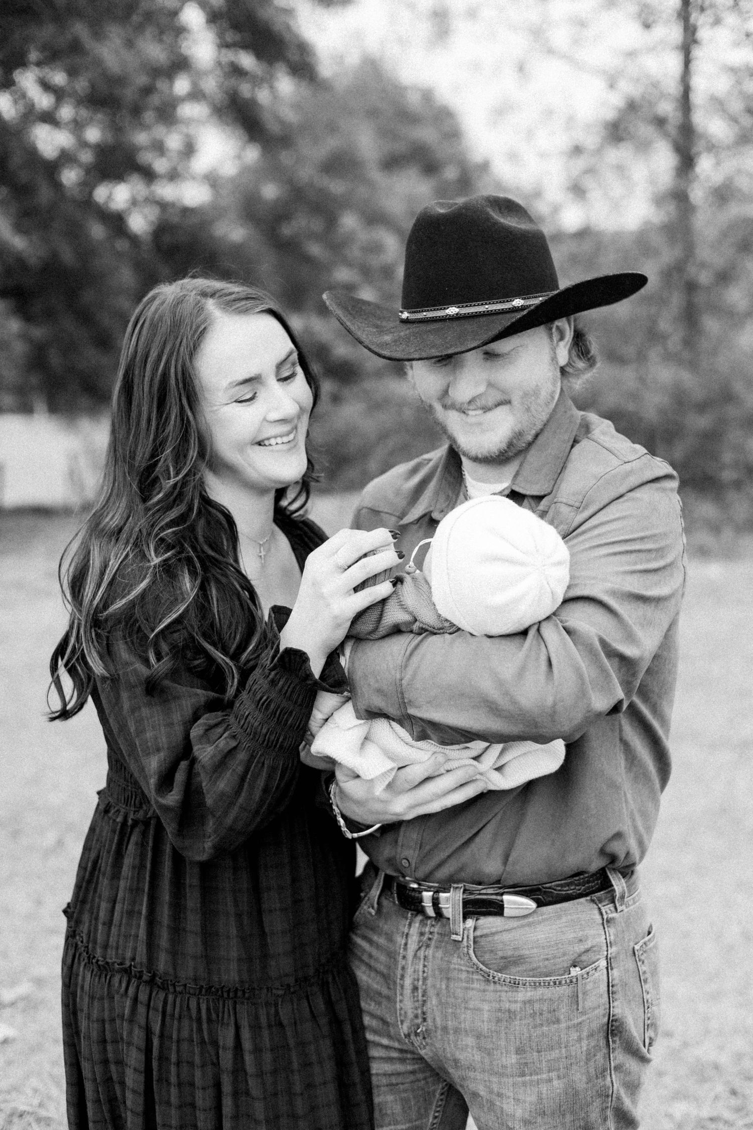Sweet family moments captured in black and white as parents hold their newborn outdoors.