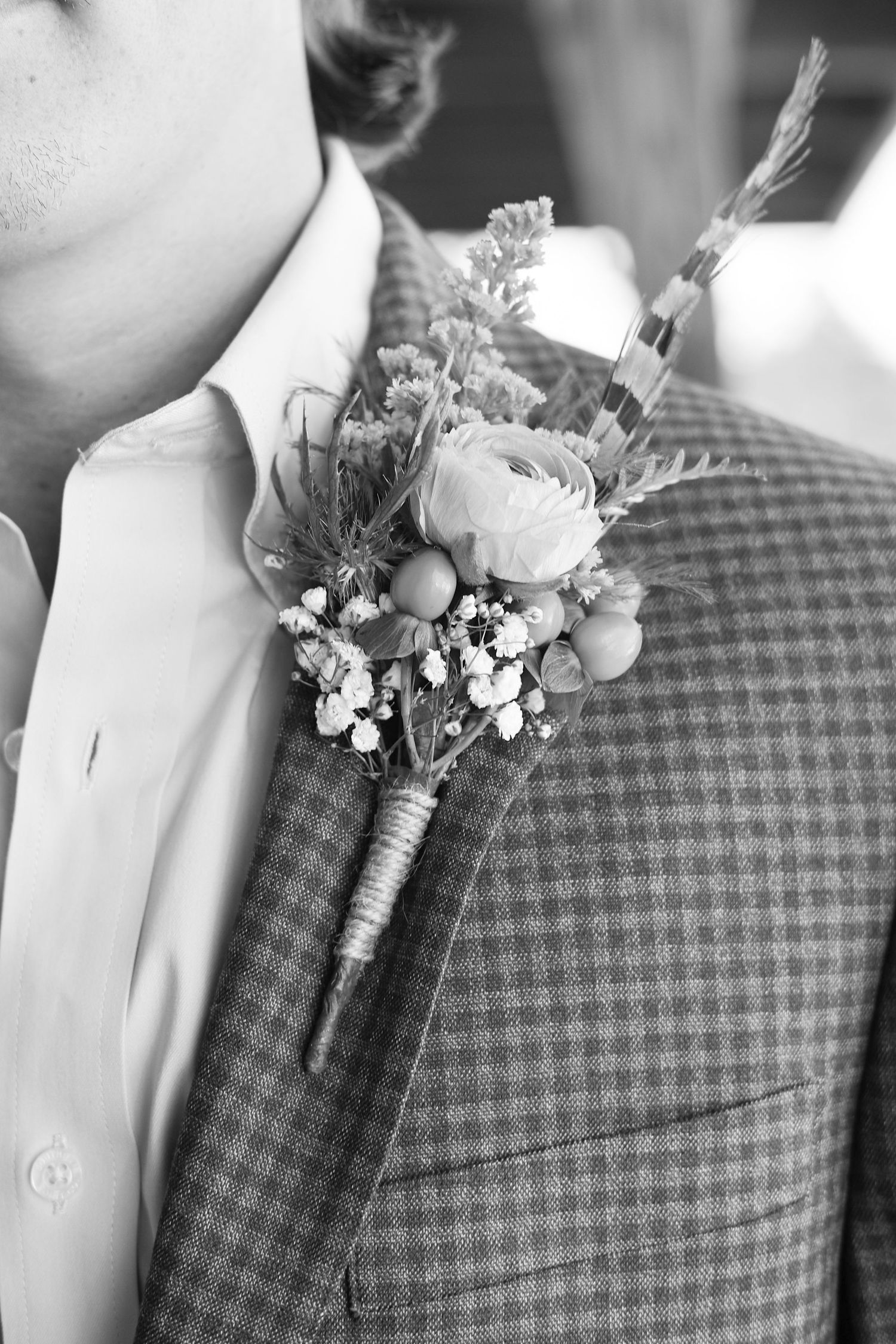 Close-up of delicate floral boutonniere on checkered suit jacket.