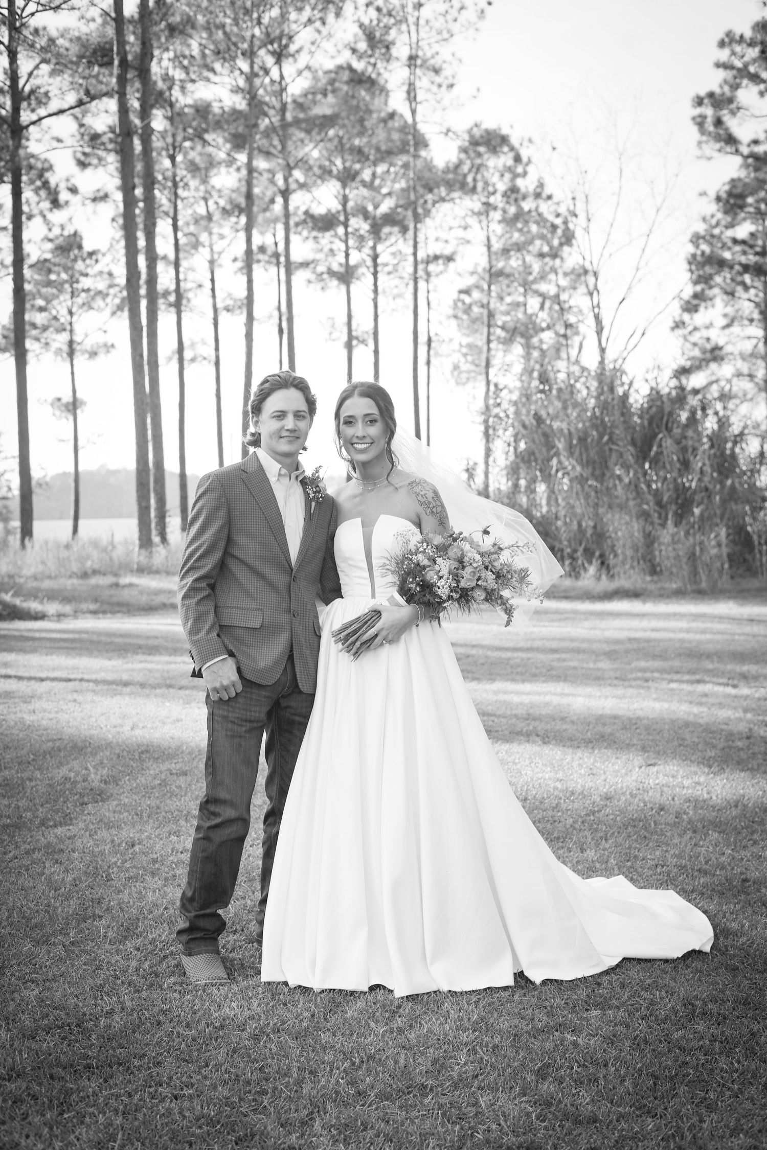 Black and white wedding photos capture a couple's intimate moments in a serene pine forest setting.