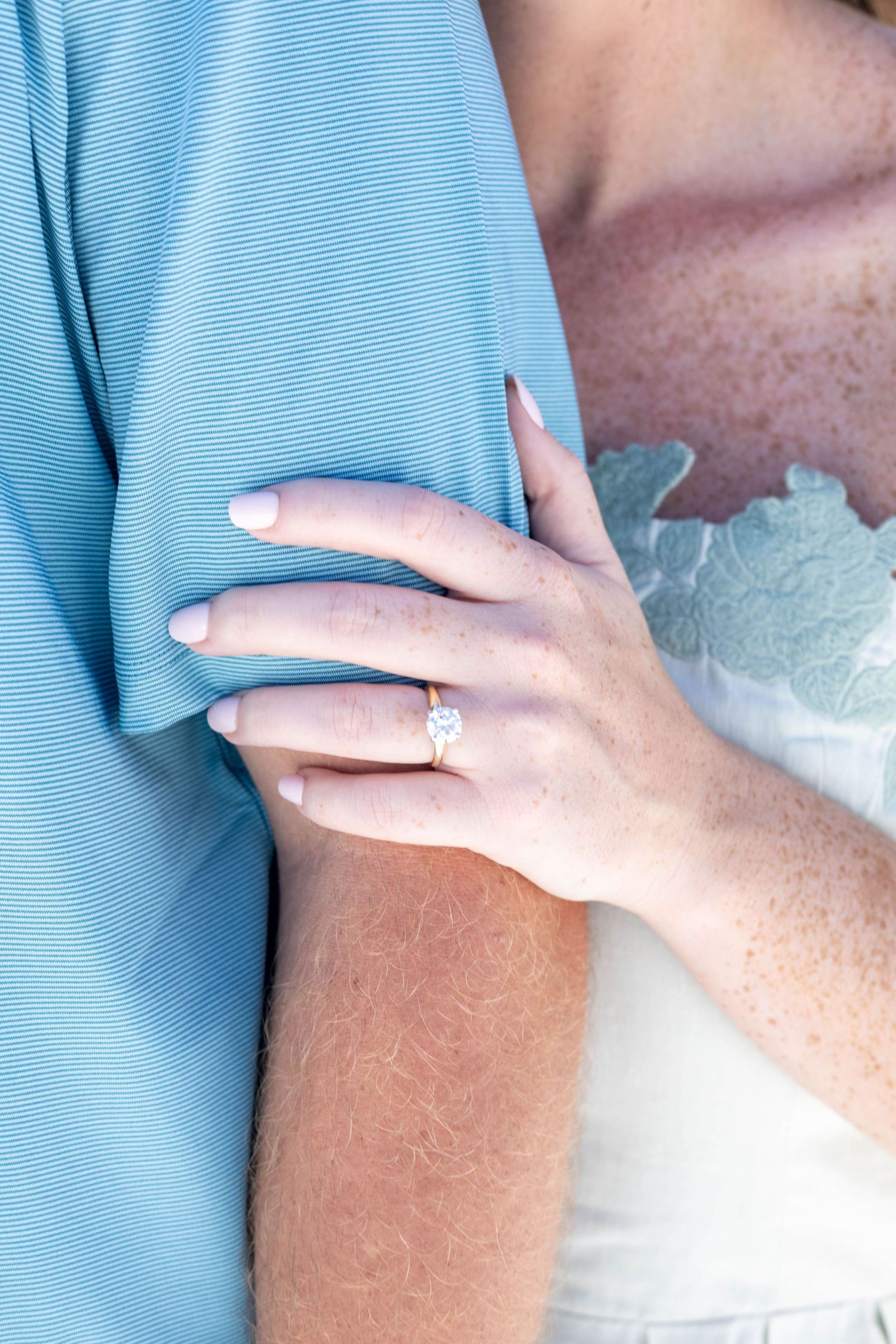 Close-up sequence showing hands wearing an engagement ring against light blue fabric.