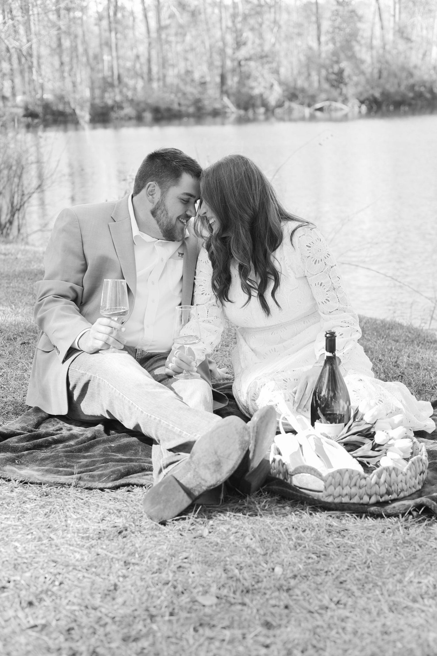 A romantic black and white photo series of a couple lying on a picnic blanket in a dreamy outdoor setting.