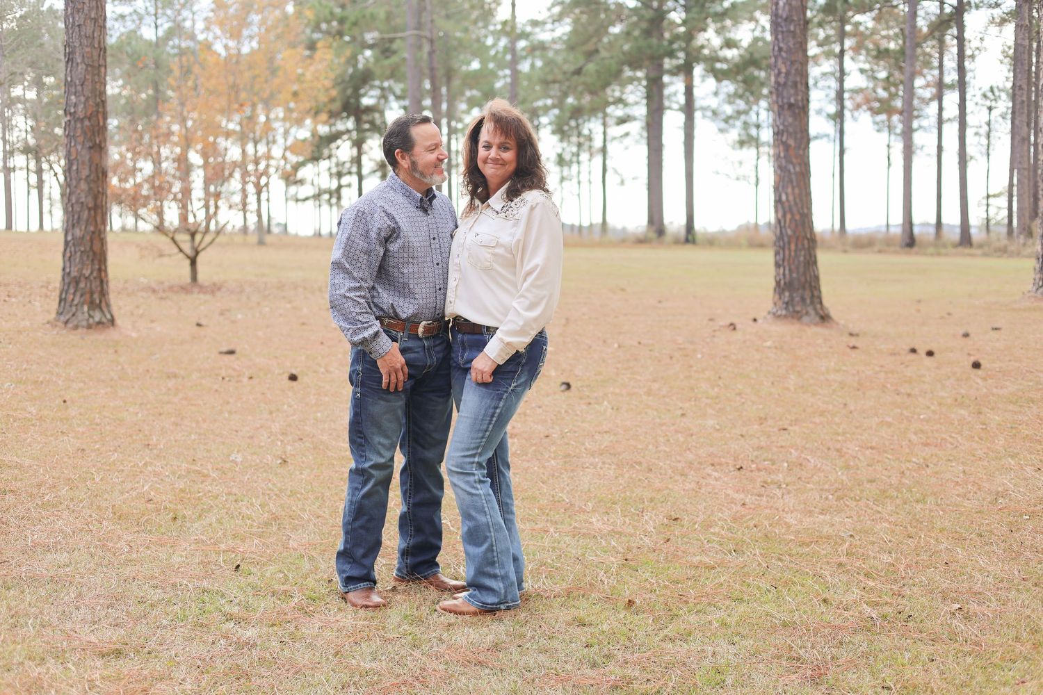 Family enjoying outdoor photo session in wooded area with pine trees and natural lighting.