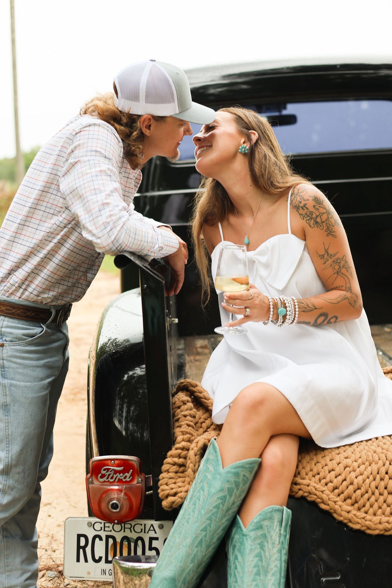 Romantic moment shared in pickup truck bed with woven blanket and drinks.