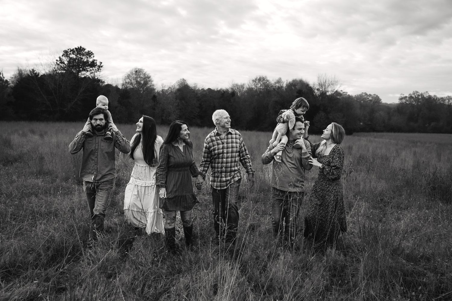 Panoramic black and white landscape shot of family members walking through a field.