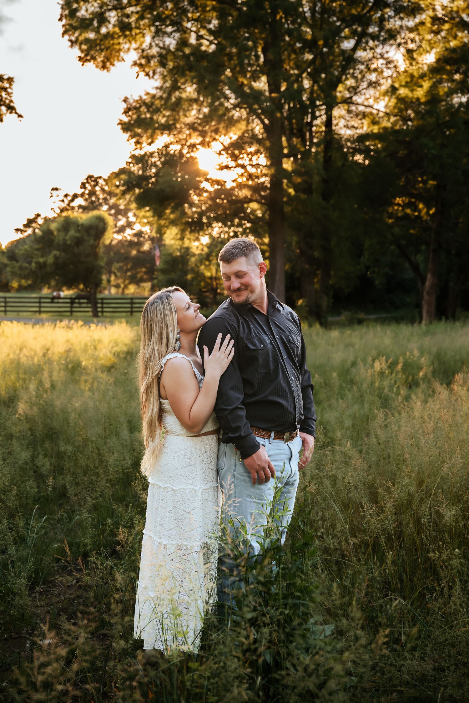 Couple embracing in golden sunset light in tall grass field.