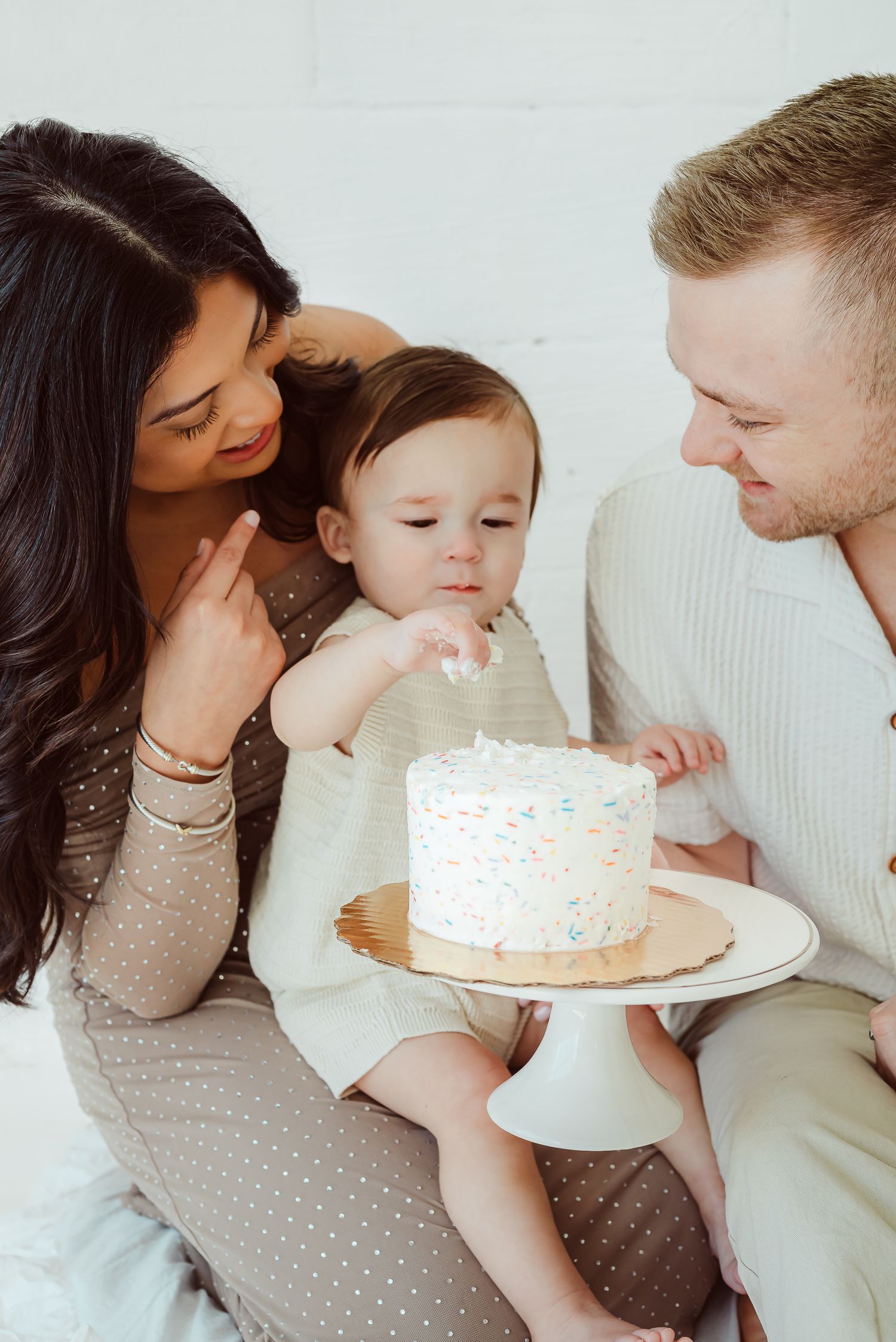 A family celebrates with a small white birthday cake during an intimate gathering.