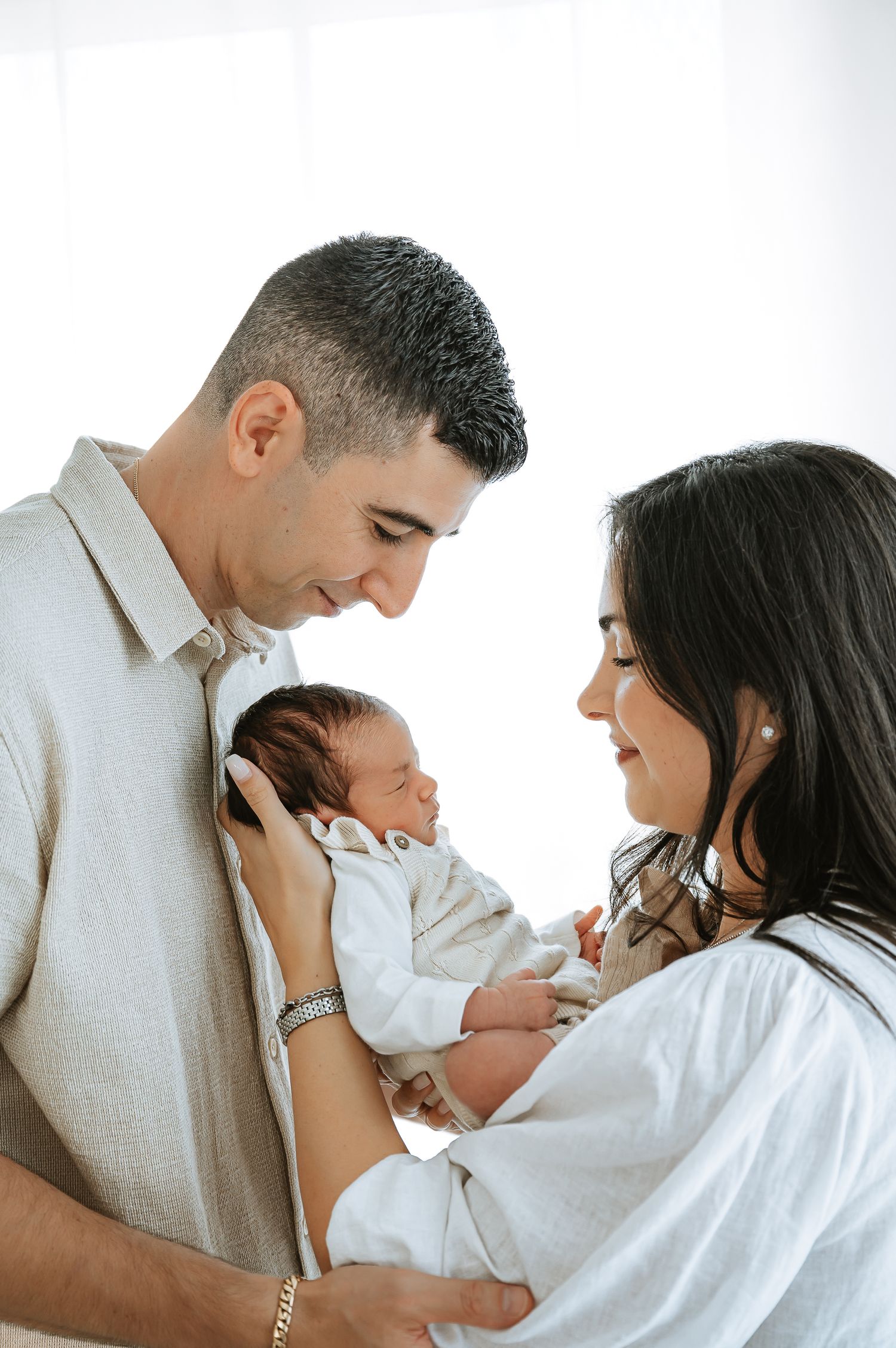 Intimate family portrait in white studio setting with soft lighting.