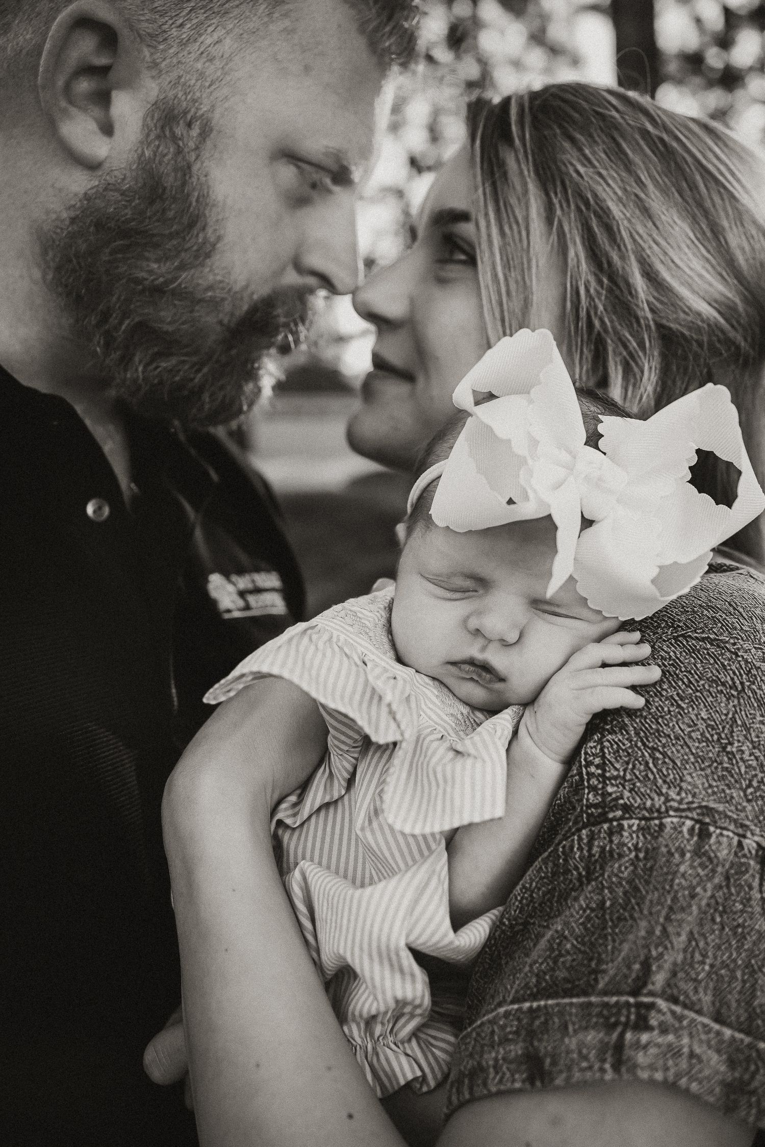 Black and white portrait of intimate family moment with sleeping baby.