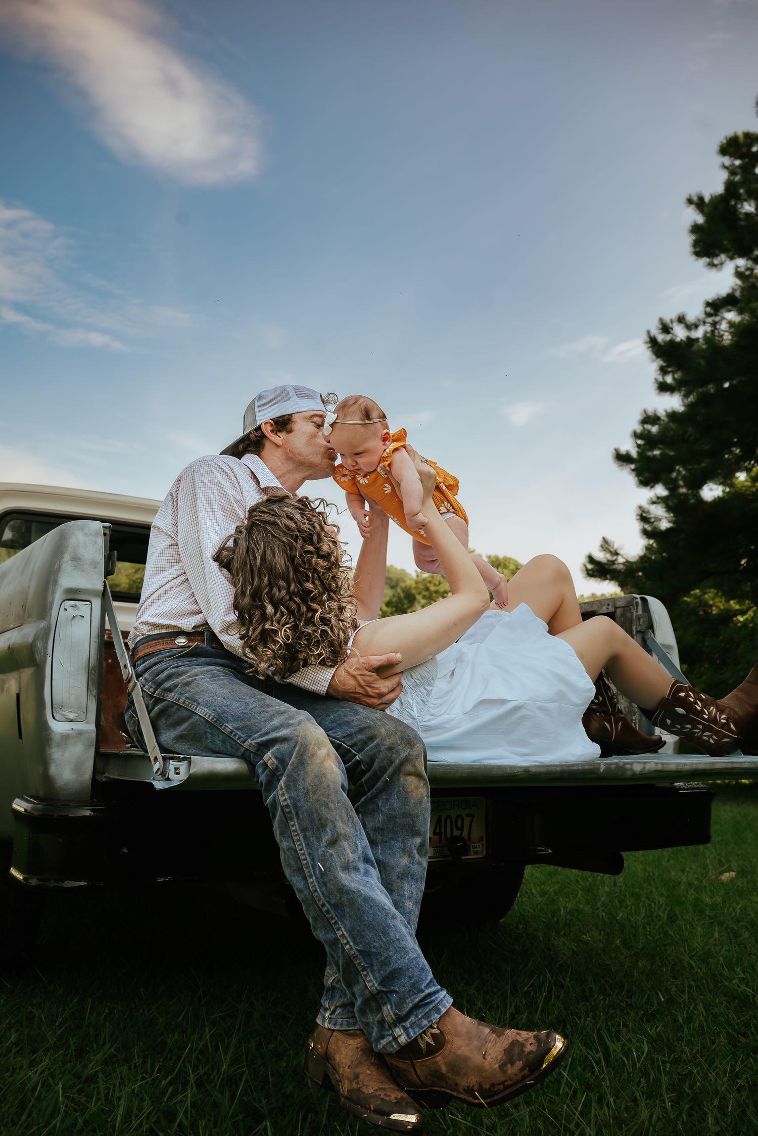 Playful couple relaxing in the bed of a pickup truck during golden hour.