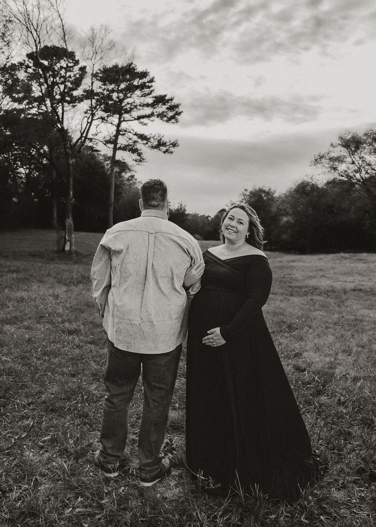 A couple shares a joyful moment in a field during sunset.