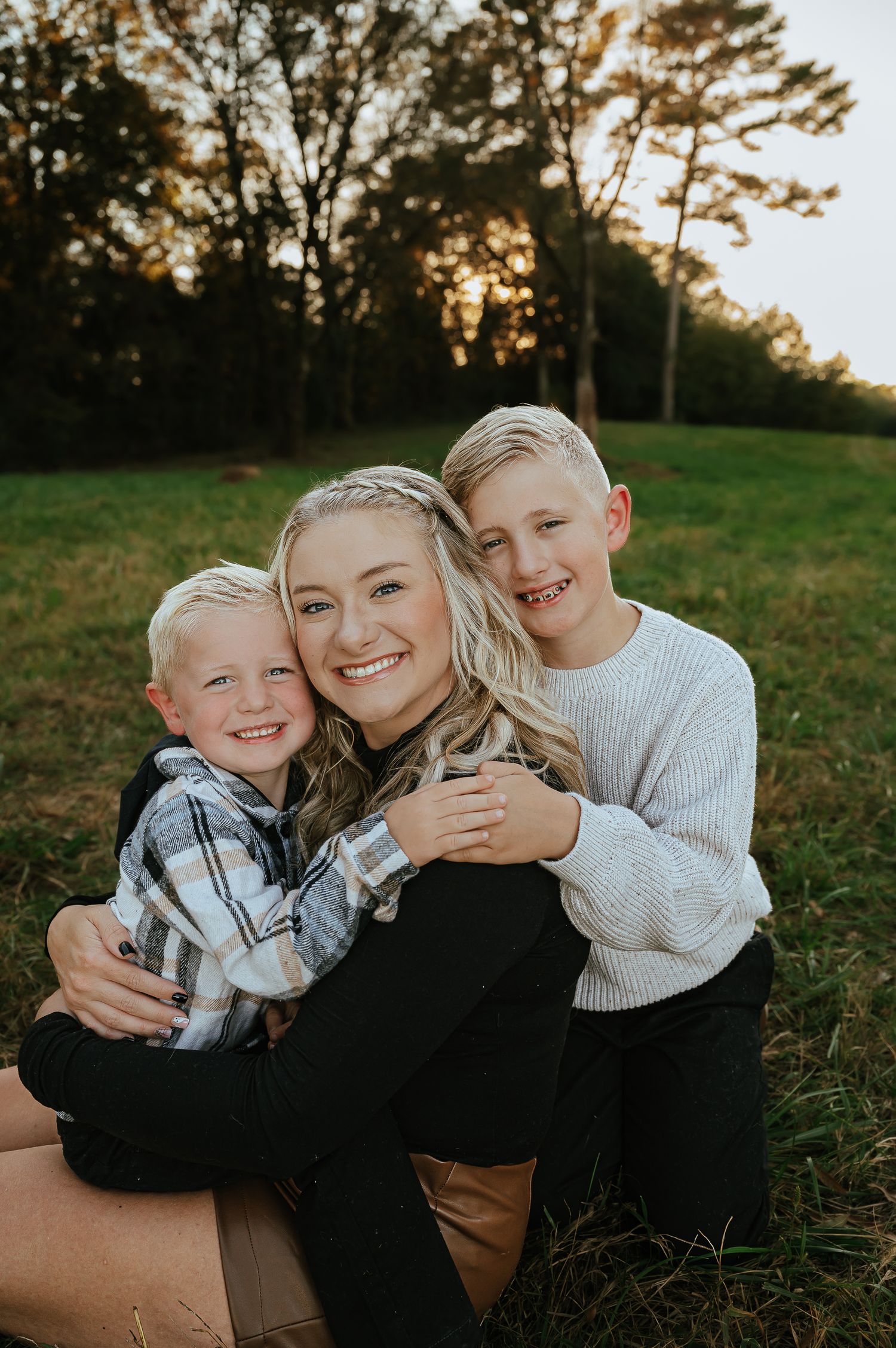 Family portrait session at sunset in a grassy field showing warm embraces and genuine smiles.