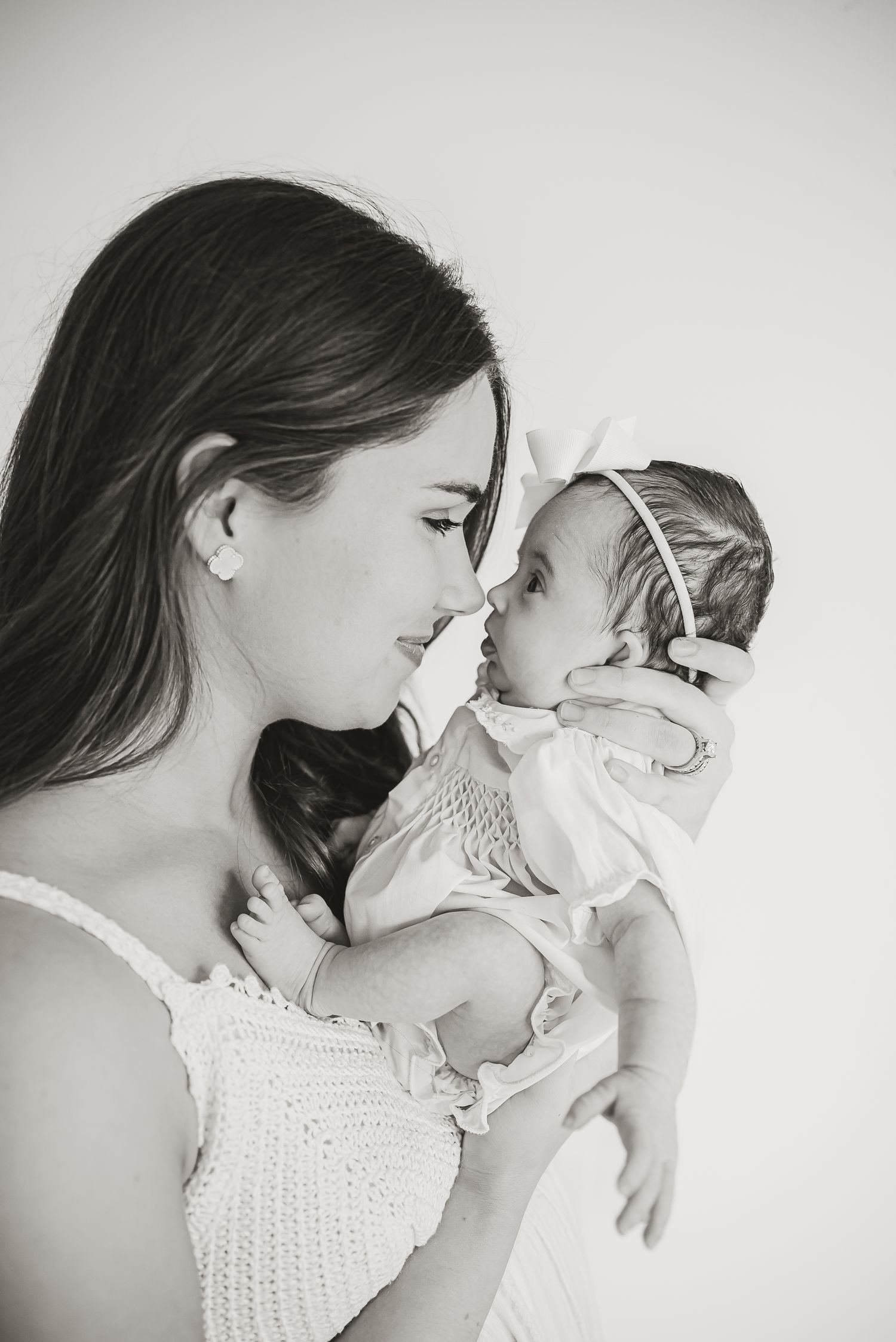 A tender black and white portrait of a mother and baby touching noses.