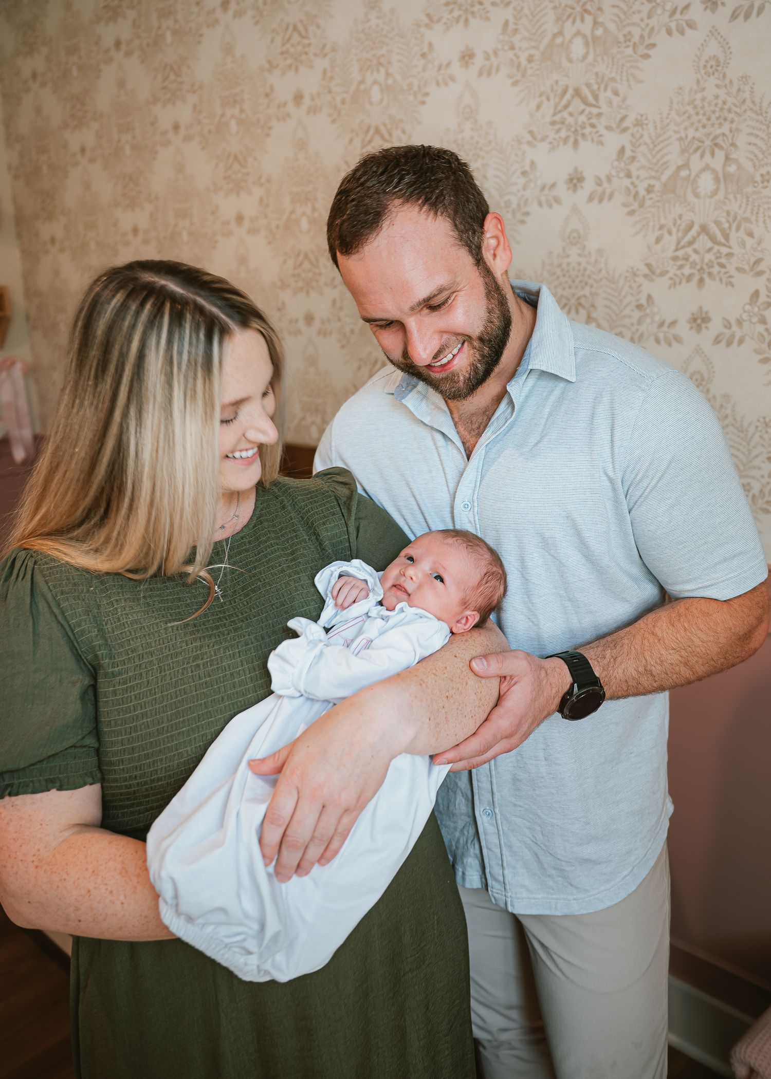 A tender moment as new parents gaze lovingly at their newborn baby in a cozy indoor setting.