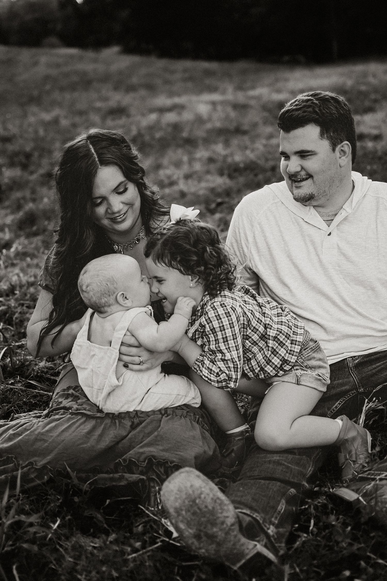 Black and white portrait of family sharing intimate moment outdoors.
