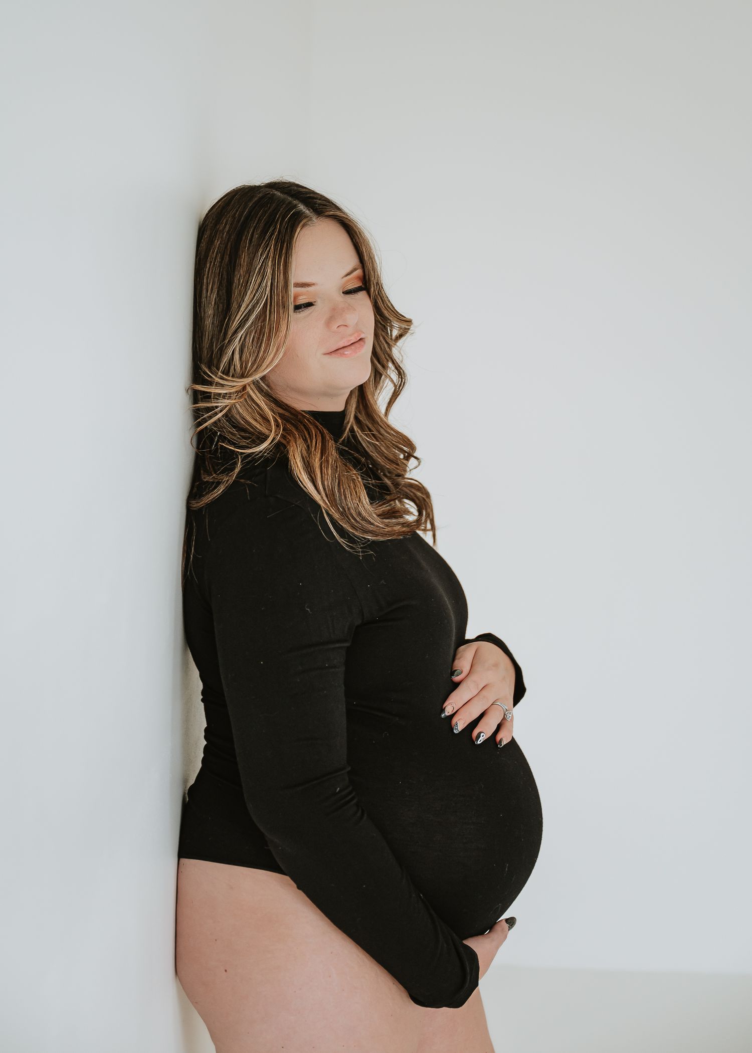 Artistic maternity photo series showing a pregnant woman in black against a white background.