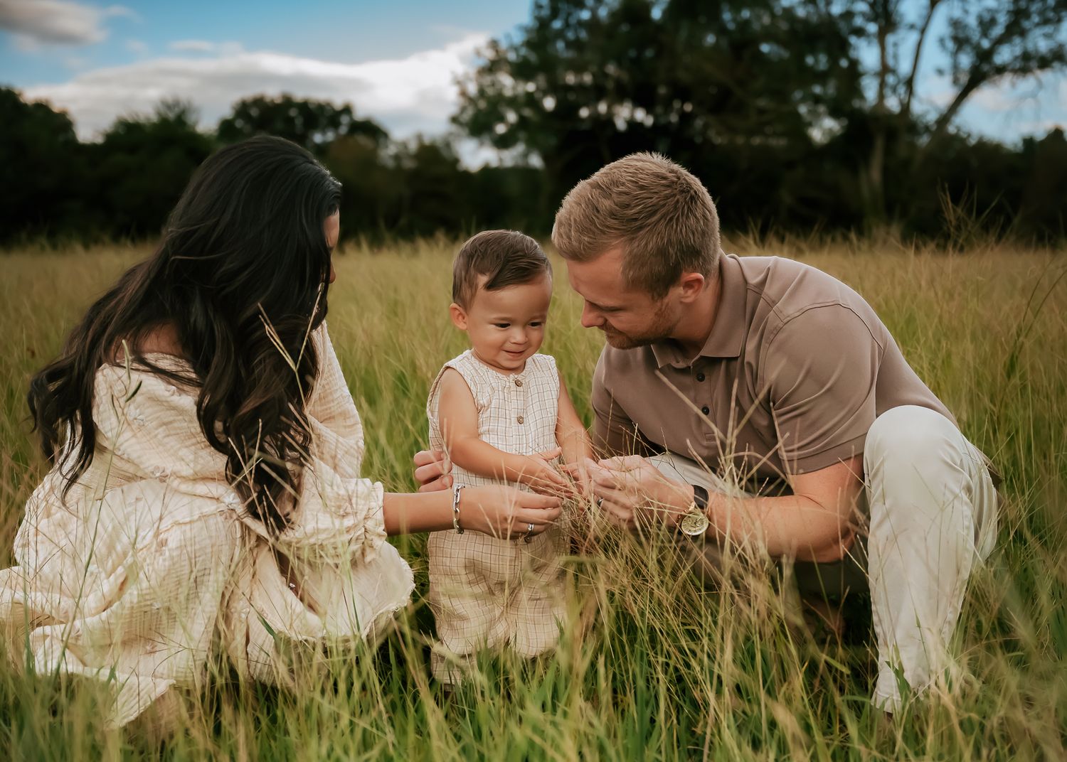 Family members sitting together in a grassy field on a sunny summer day.