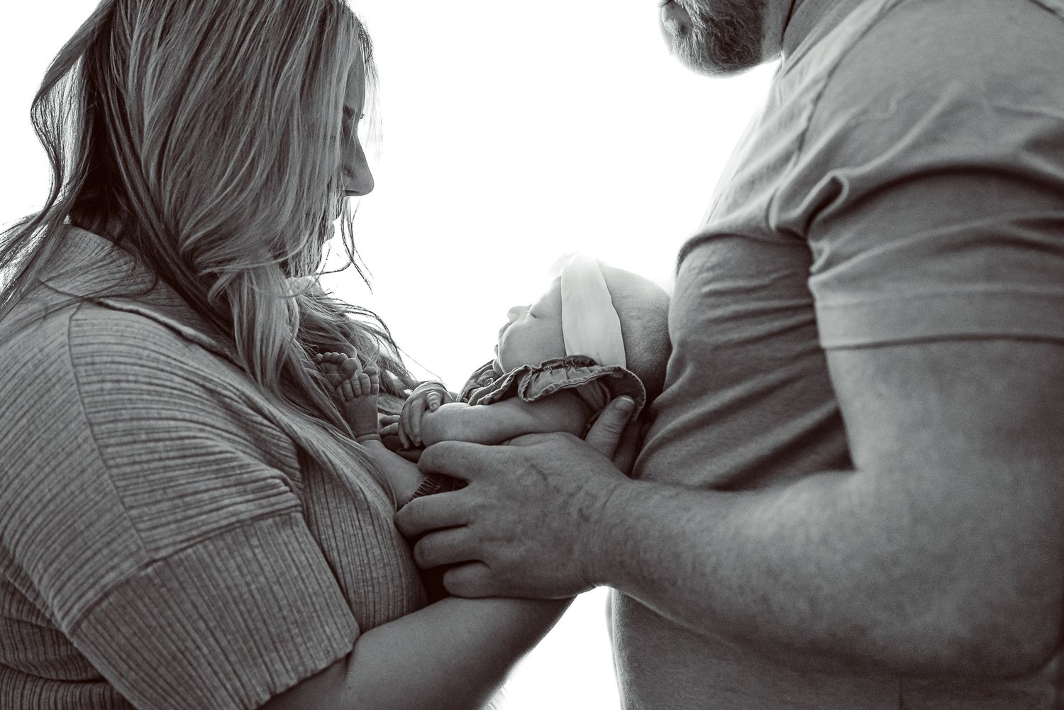 A black and white intimate moment of parents holding their newborn baby.