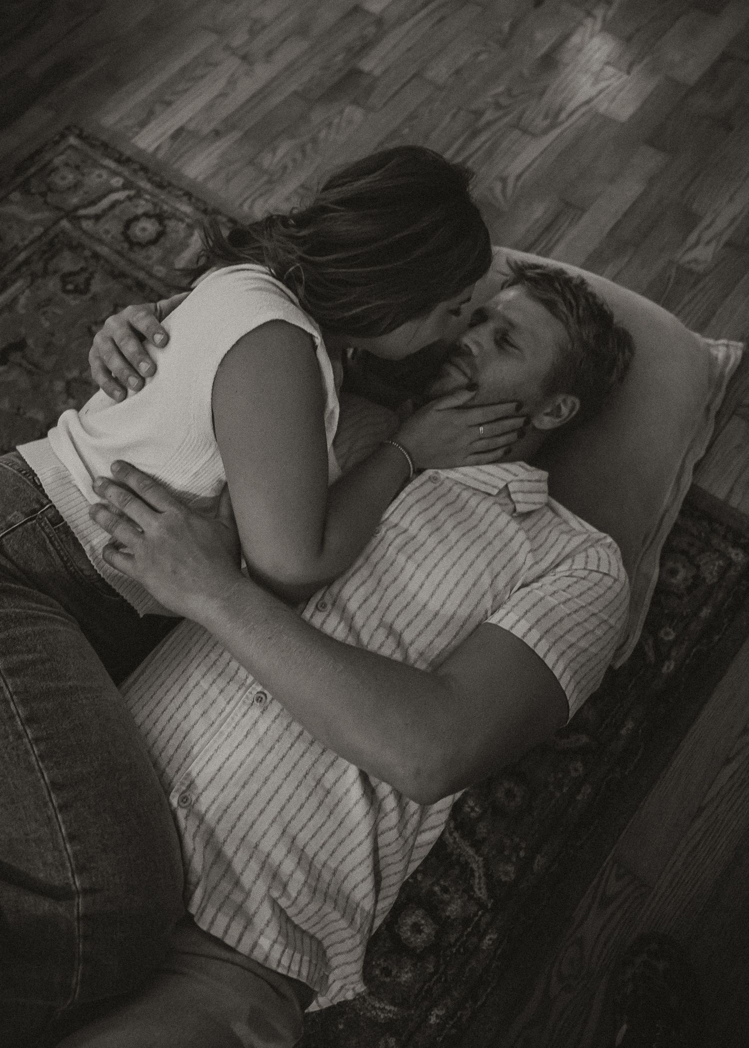 Black and white intimate photos of couple cuddling on wooden floor.