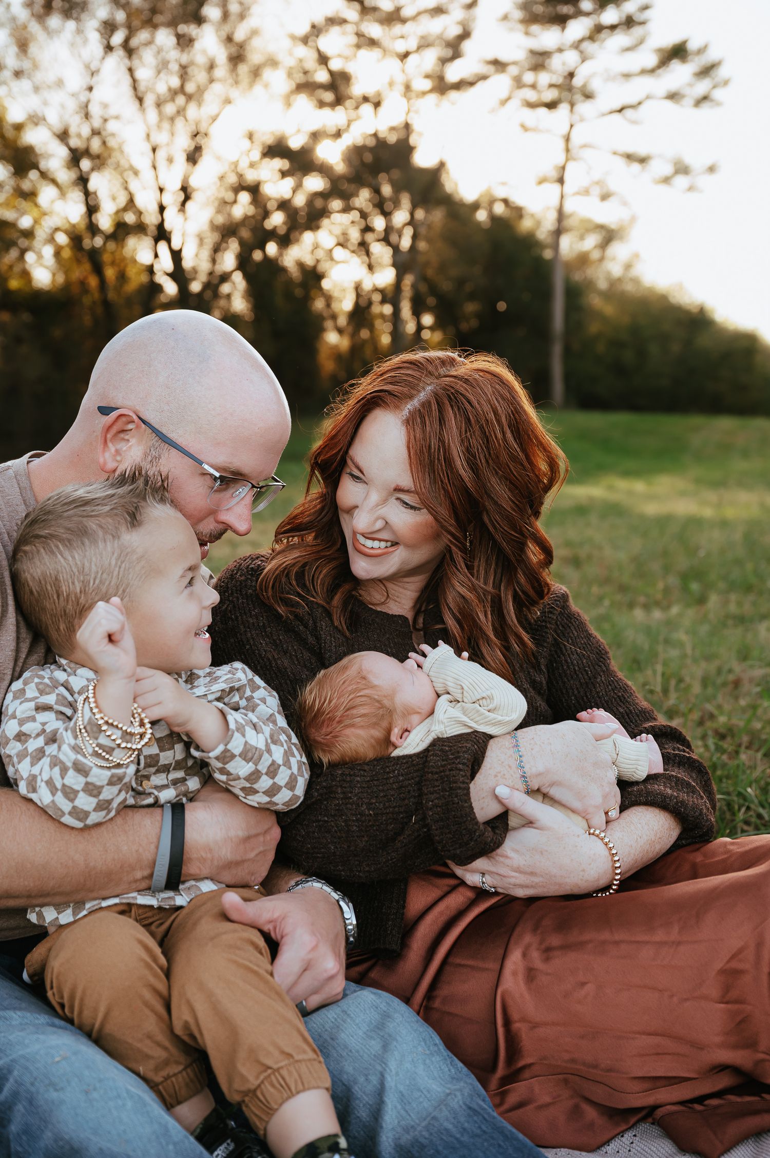 A tender family moment captured outdoors during golden hour with a natural backdrop.