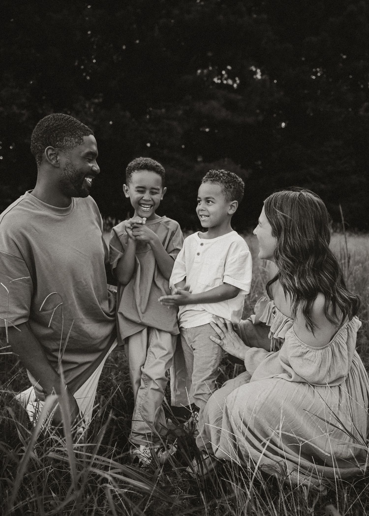 Black and white candid photo of a family sitting together in tall grass.