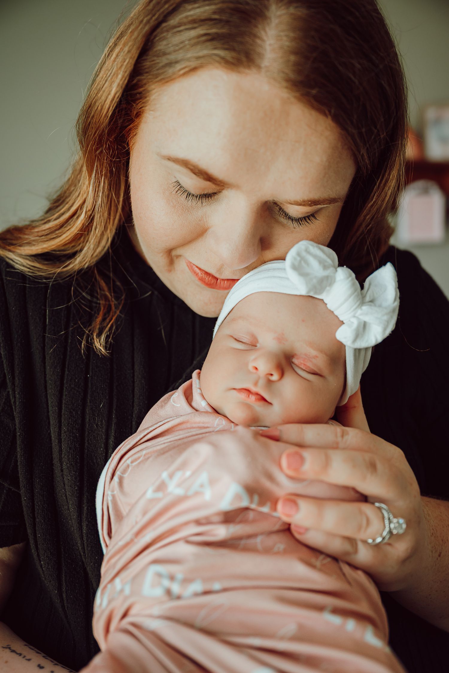 A tender moment captured between a sleeping baby in pink and their caregiver.