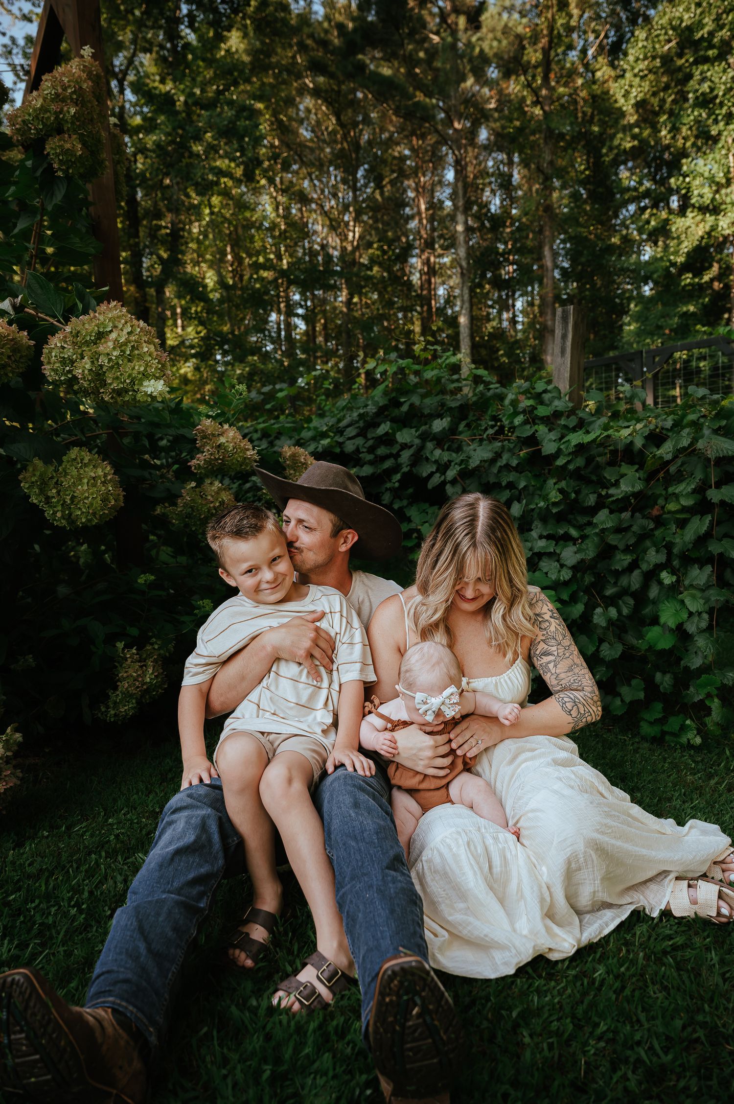 A family relaxing together on grass with forest greenery in the background during golden hour.