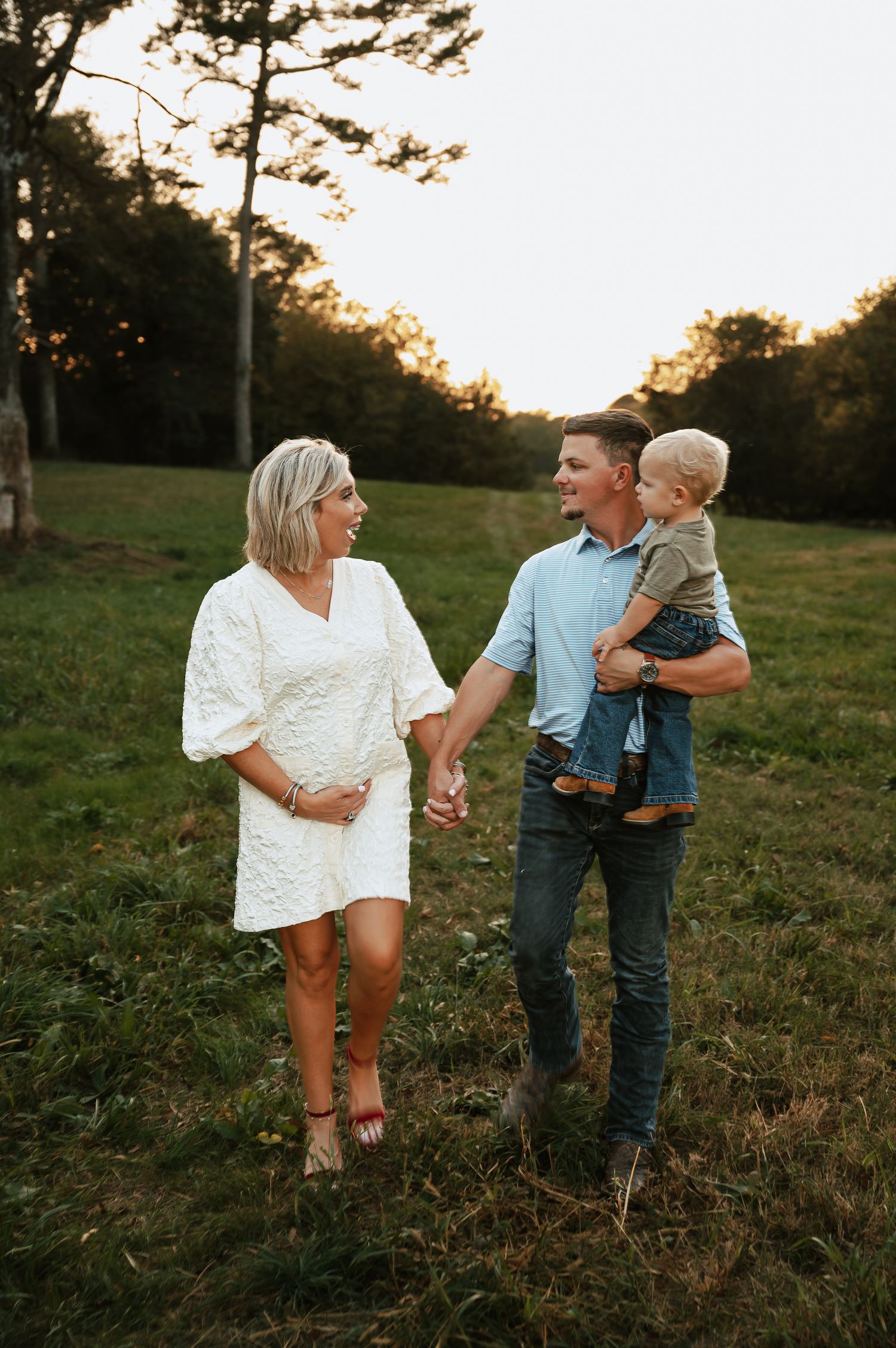 A family walks together through a golden field at sunset.