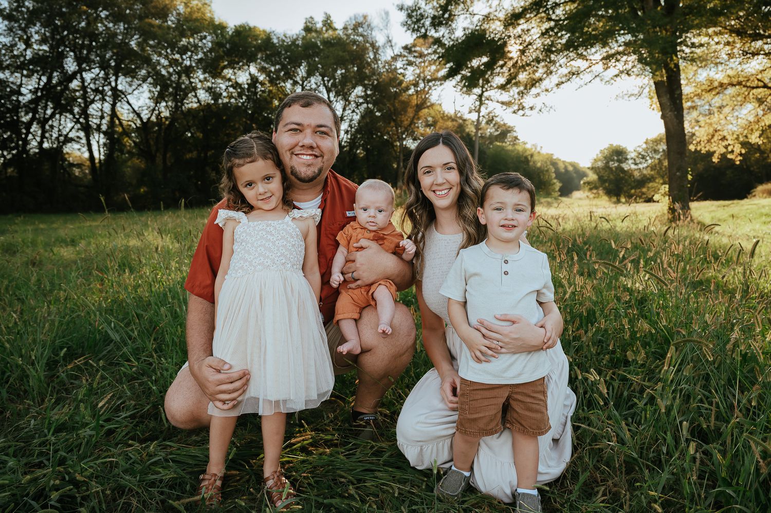 Outdoor family photoshoot in a natural setting during golden hour.