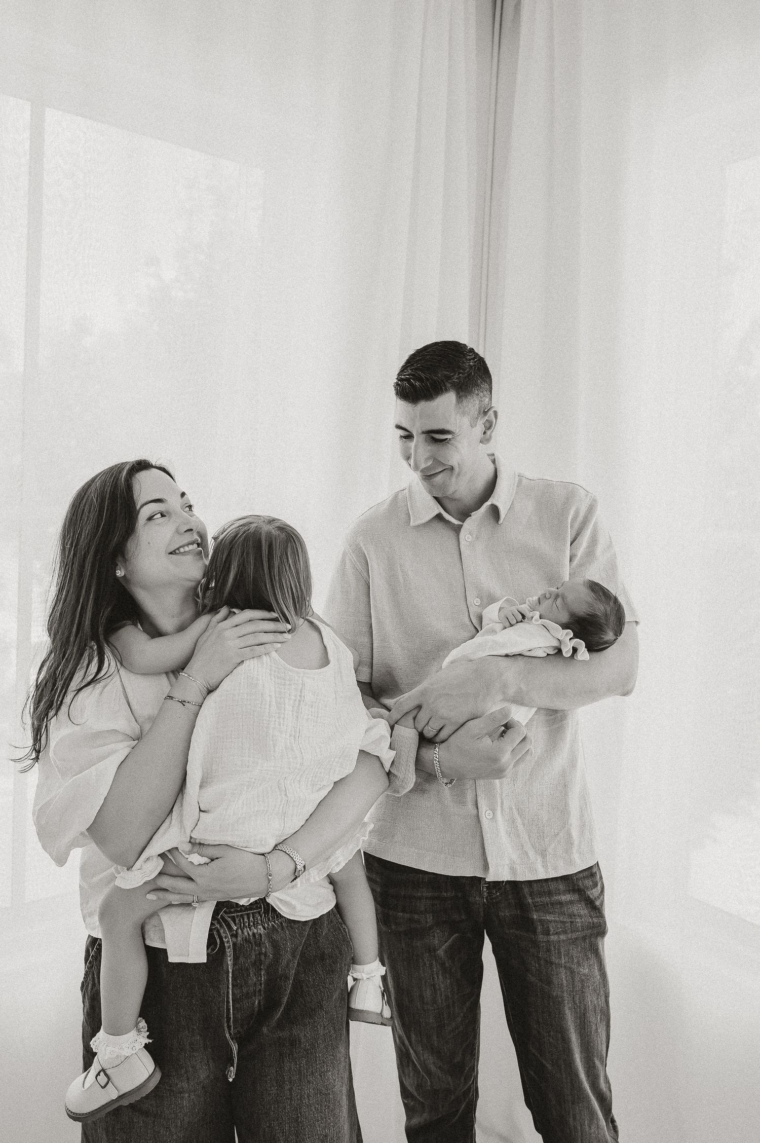 Black and white photos of a family sharing joyful moments with their newborn.