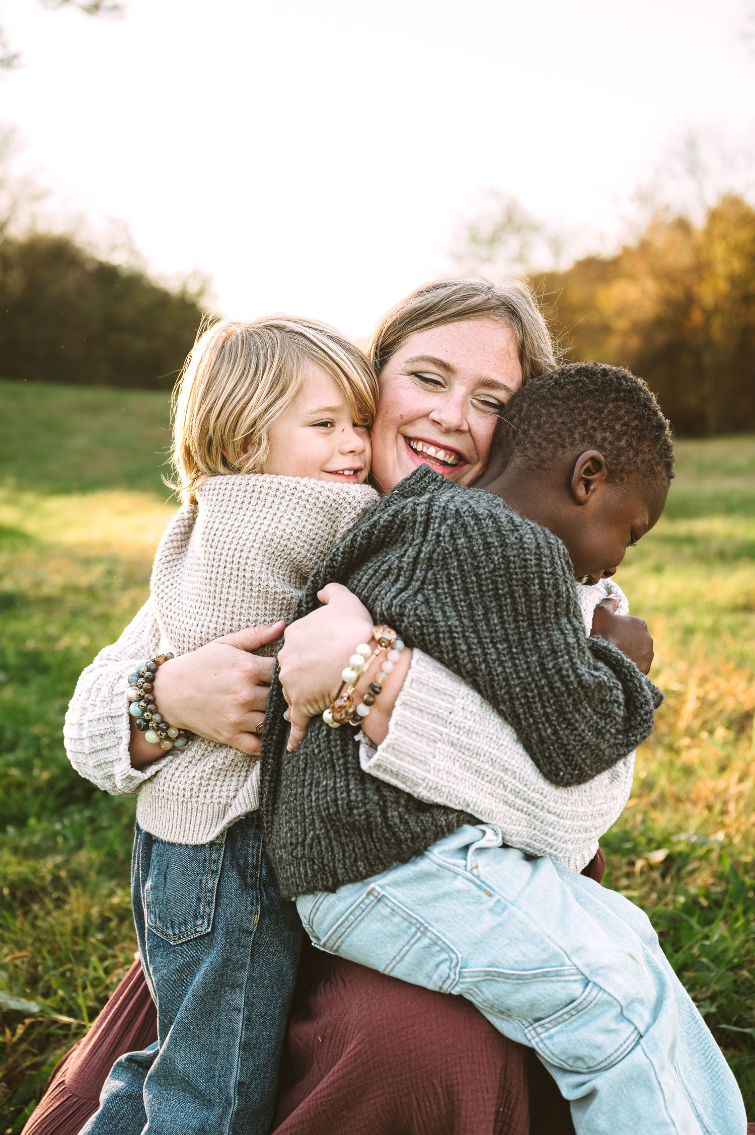 Joyful group hug outdoors during golden hour in autumn field.