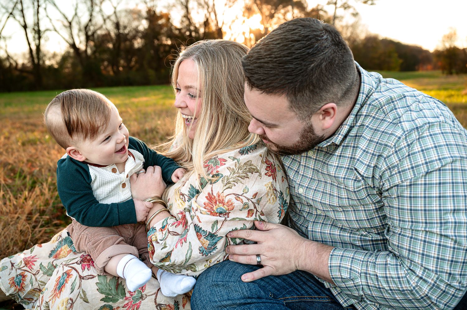 Family sharing playful moments together during outdoor sunset photo session.