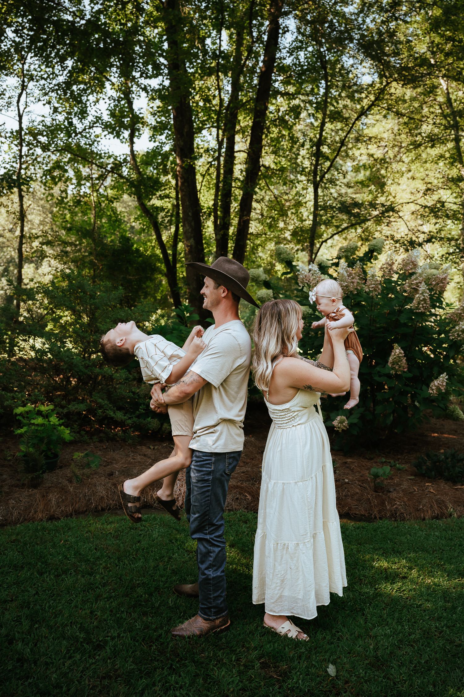 A family dancing together in a backyard garden setting with trees in the background.