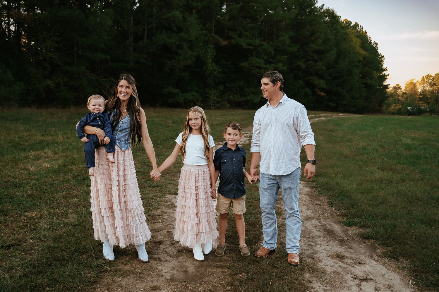 Family of five walks together along path during sunset photo session.