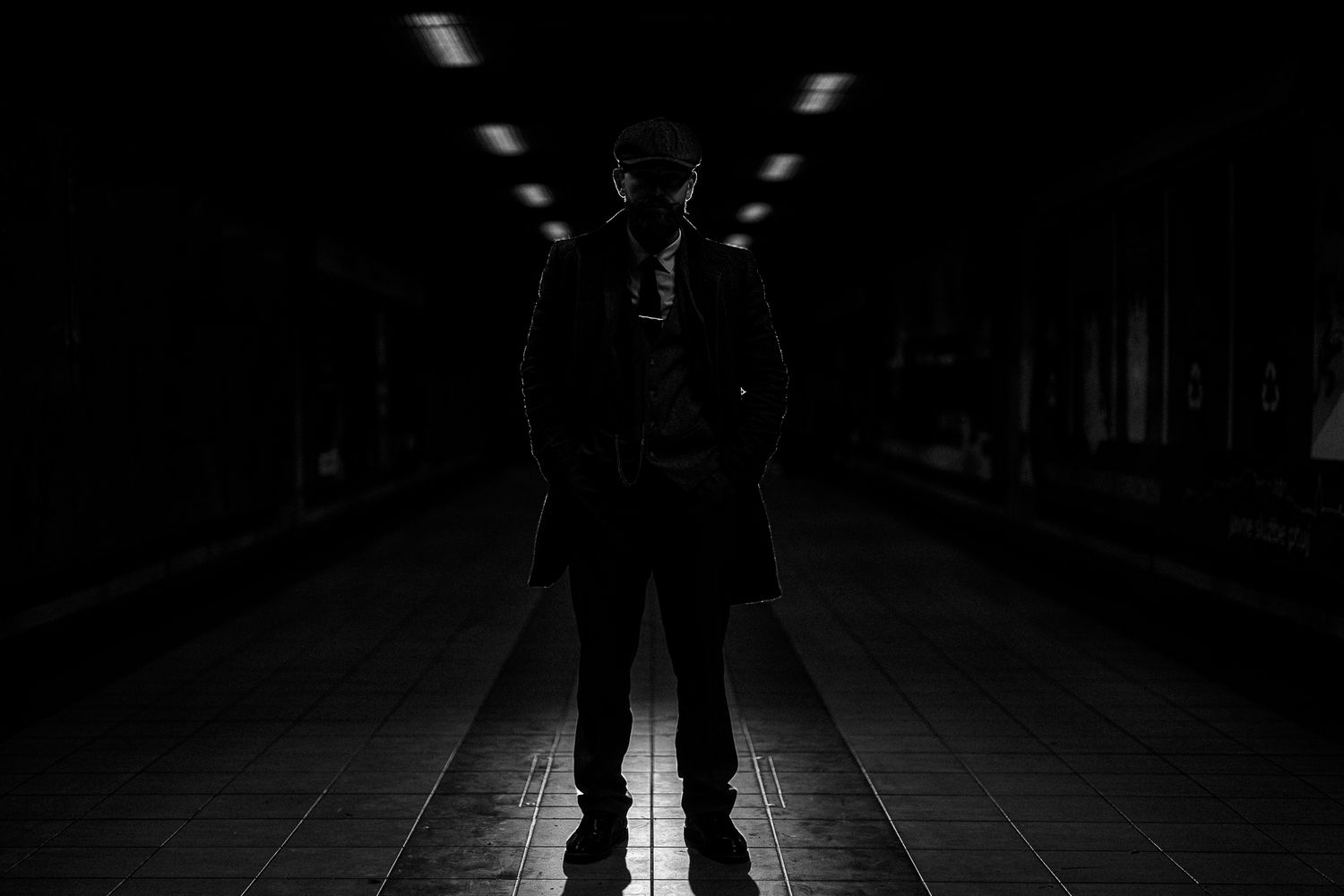 Silhouetted figure in dark corridor with symmetrical lighting pattern.