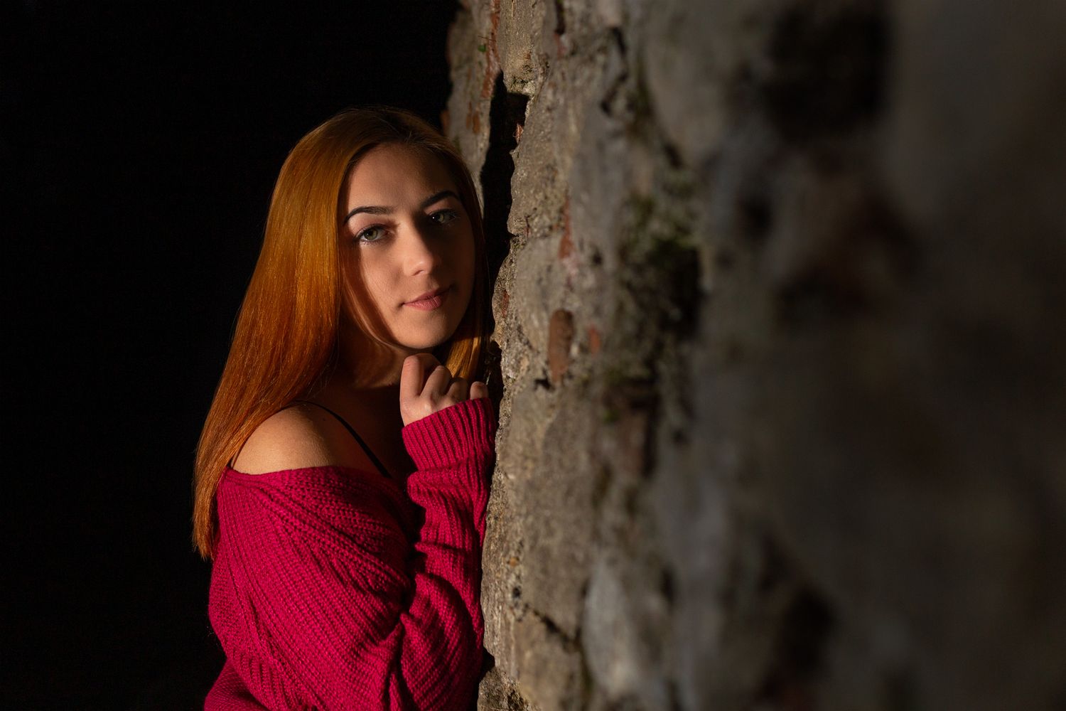 Dramatic portrait series against dark tree bark in red sweater.