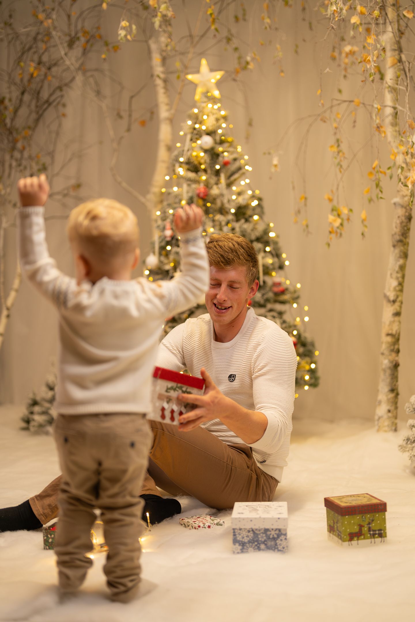 Playful holiday photoshoot with Christmas decorations and wrapped presents.