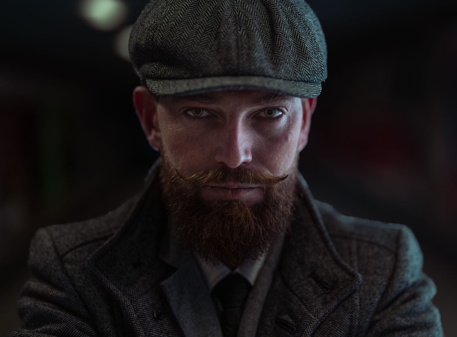 Dramatic portrait of person wearing flat cap and dark clothing in low-key lighting.