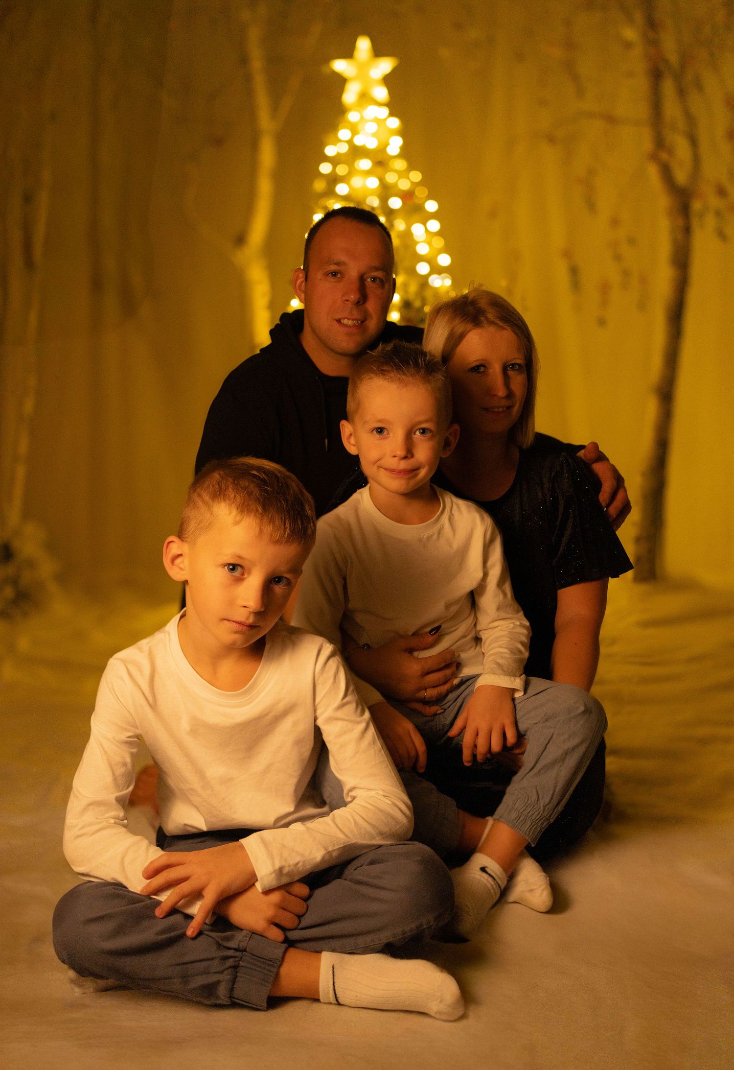 Cozy Christmas photoshoot with string lights creating warm ambiance.