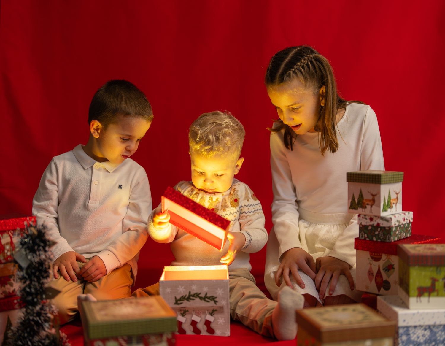Children opening glowing presents in a dark room with red lighting.
