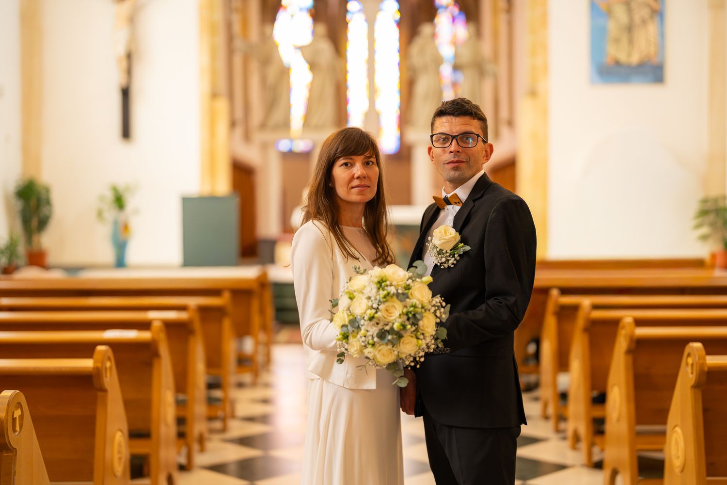Wedding ceremony in a traditional church with Gothic architecture and natural light streaming through windows.