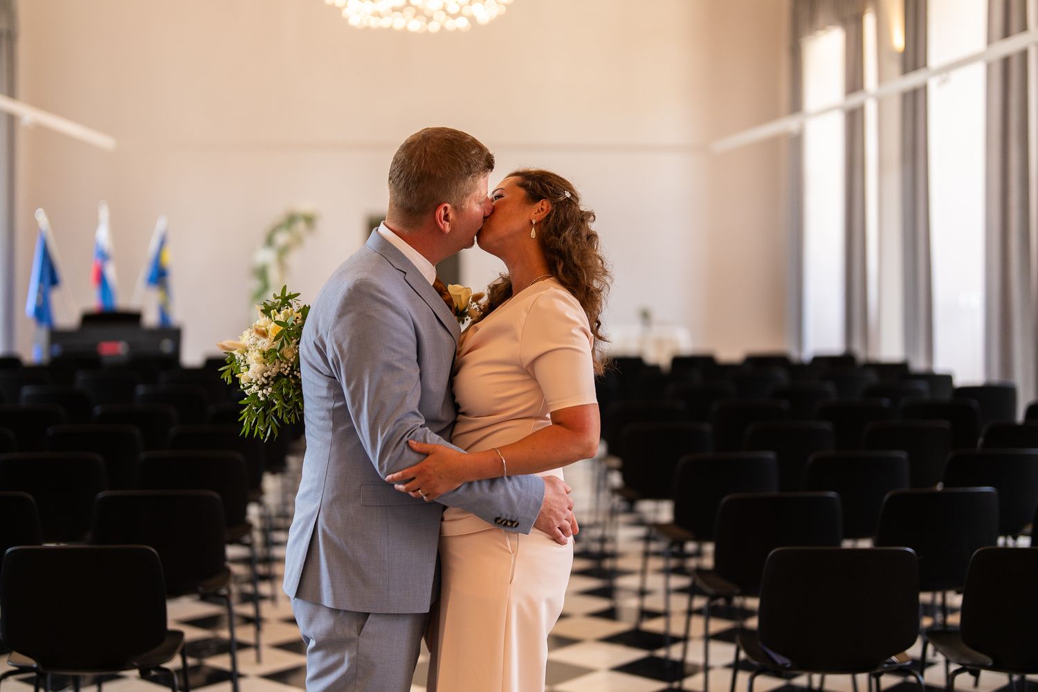 Wedding ceremony venue with rows of black chairs and elegant white decor.