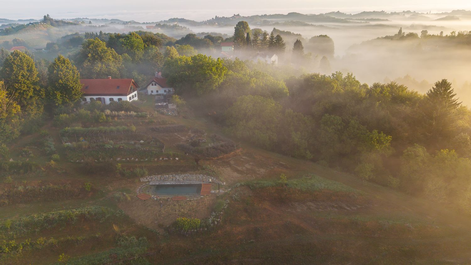 Misty panoramic landscape view of rolling hills and countryside at sunrise.
